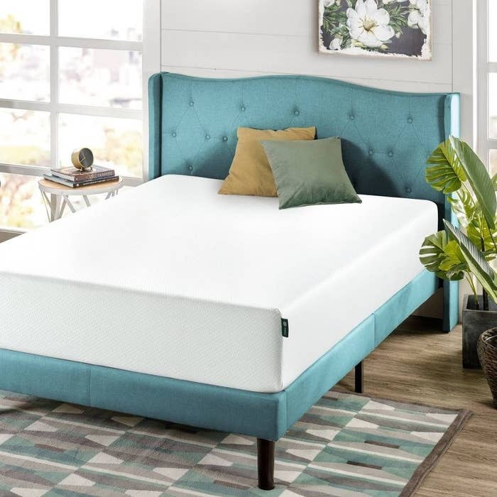 A white mattress on a blue bed frame