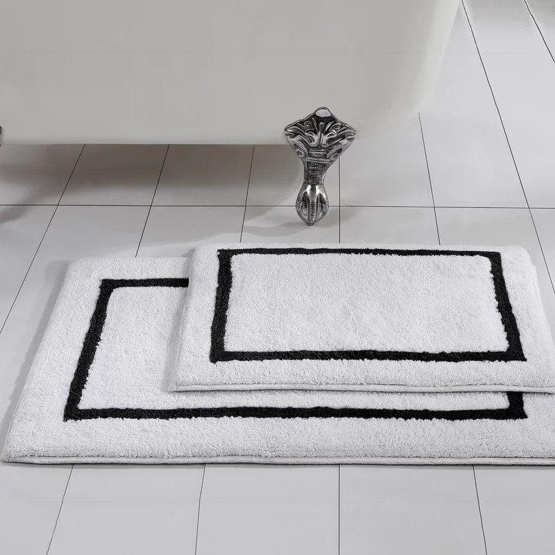 two black and white bath mats in front of a claw foot tub