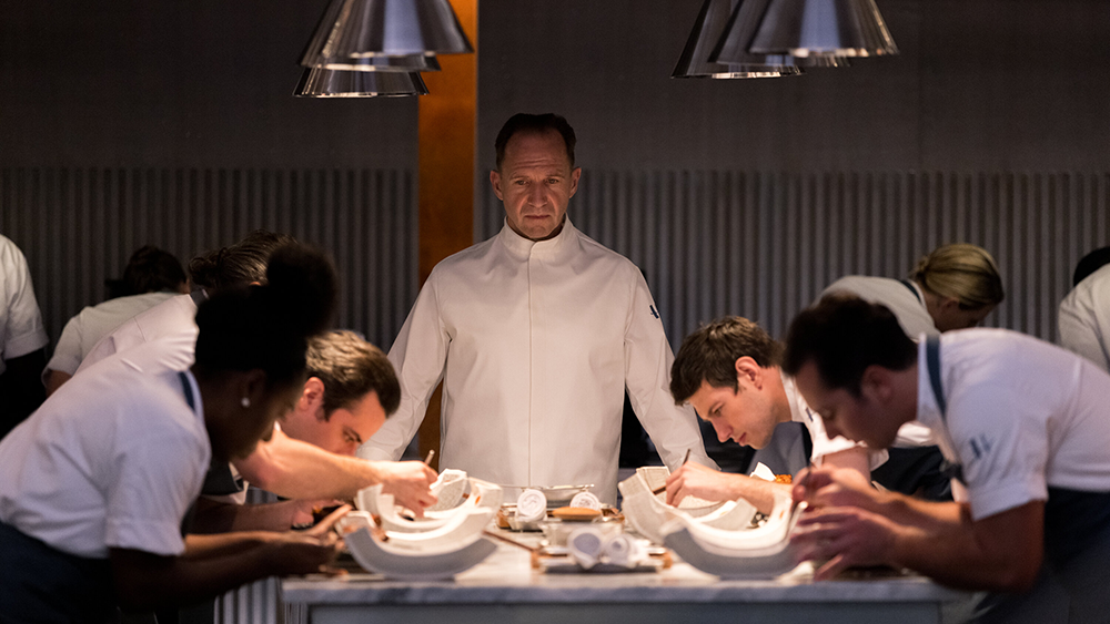 Julian Slowik (Ralph Fiennes) stands over his line cooks as they essemble dishes.