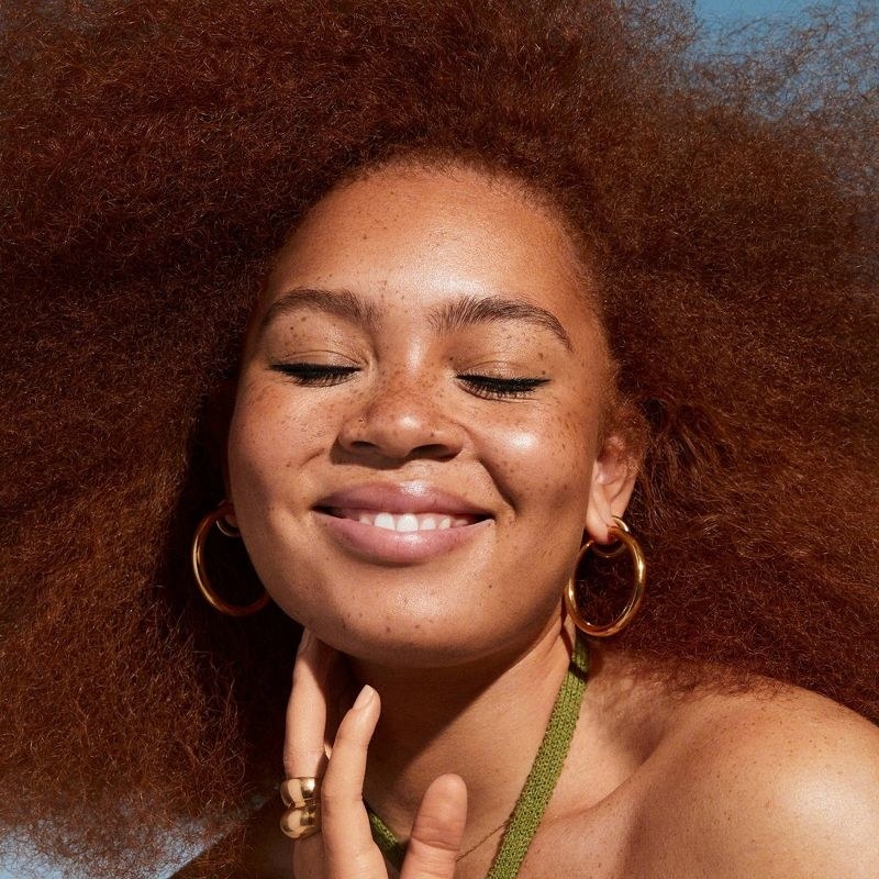 A person with a large afro showing off a glow-y complexion