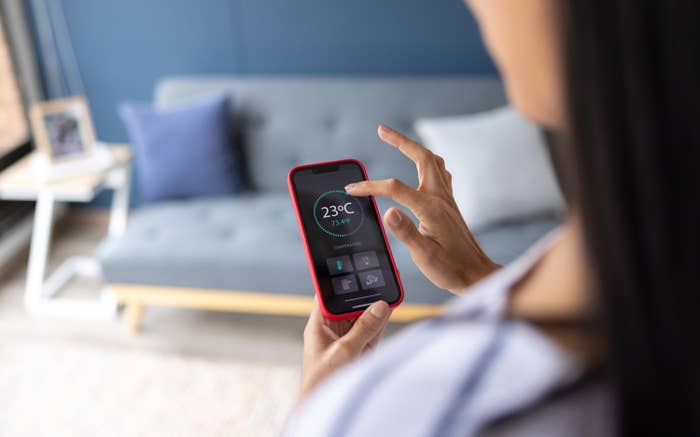 Woman controlling the thermostat on her phone