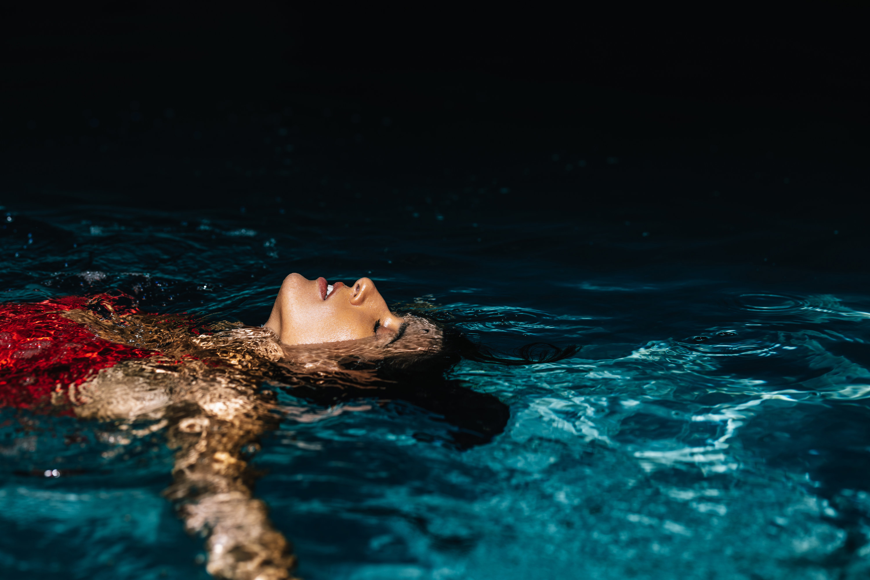 woman floating in the pool at night