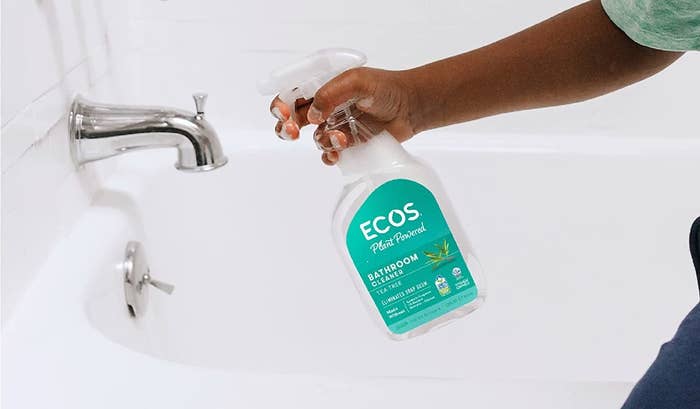 a model spraying a bottle of ecos bathroom spray