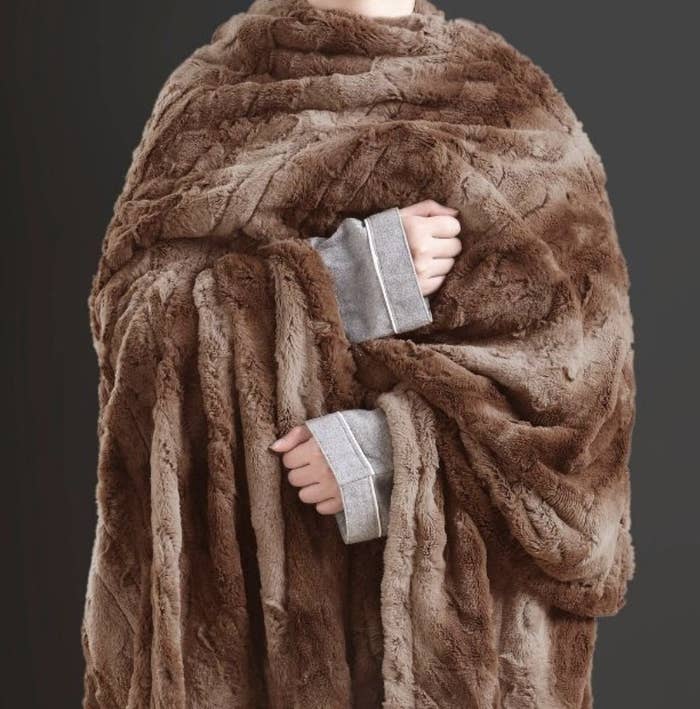 A model holds the soft brown blanket
