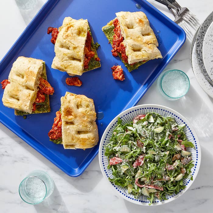 platter of chicken focaccia sandwiches next to a large bowl of salad
