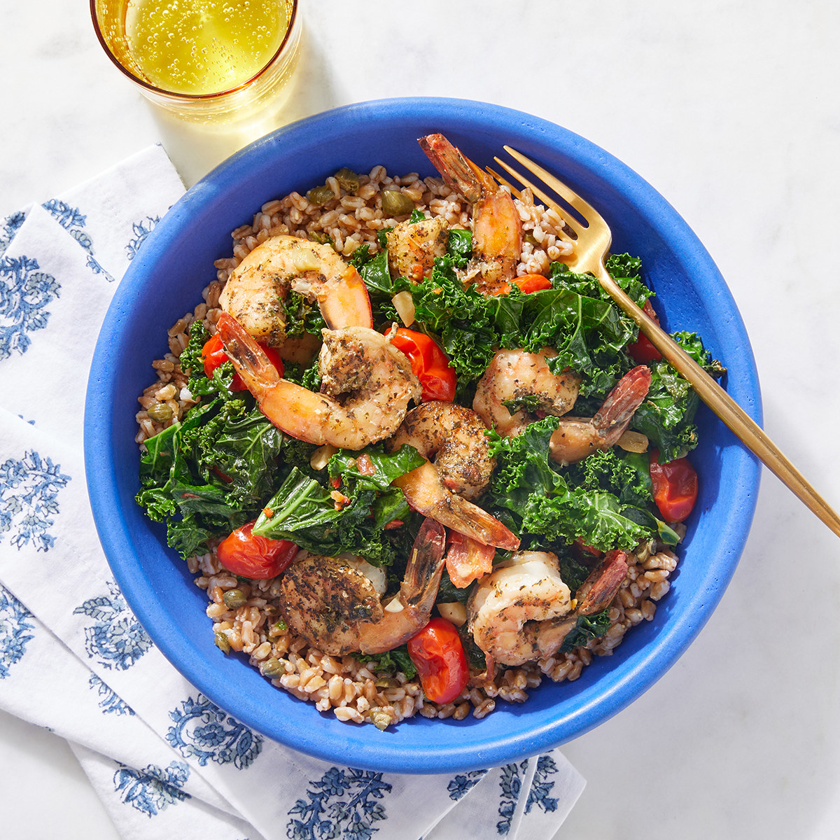 bowl of farro topped with grilled shrimp and kale and grape tomatoes