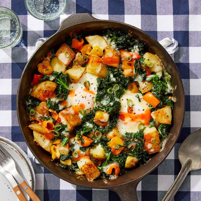 skillet of cheddar and kale hash with baked eggs