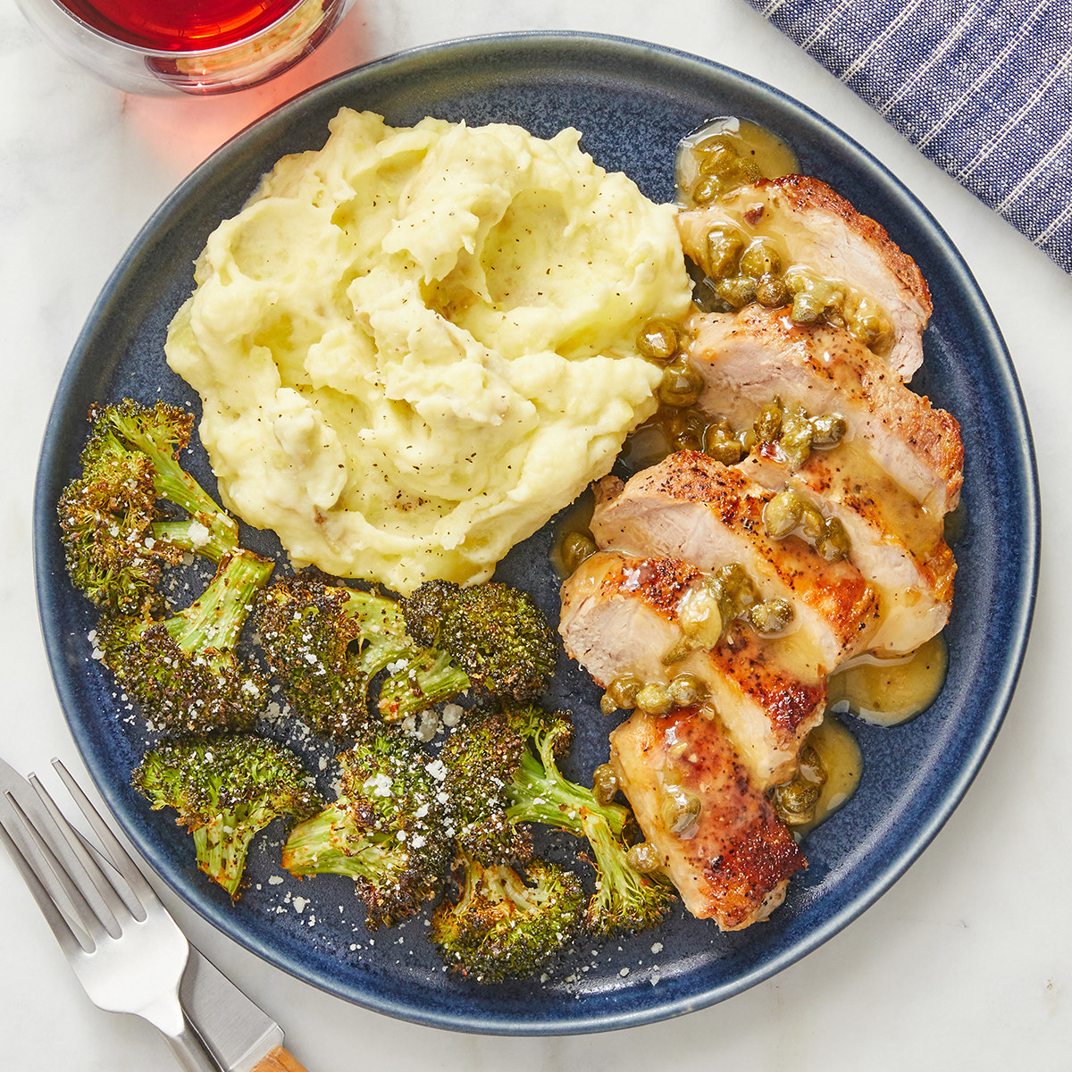 plate of garlic mashed potatoes and broccoli and pork chops with lemon caper sauce