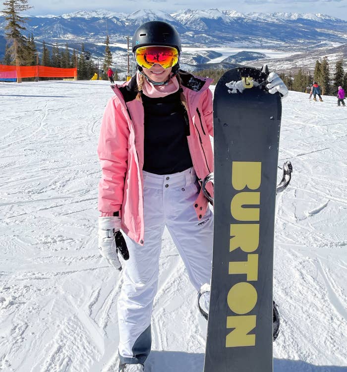 Reviewer out on the slopes in the white snowpants with snowboard