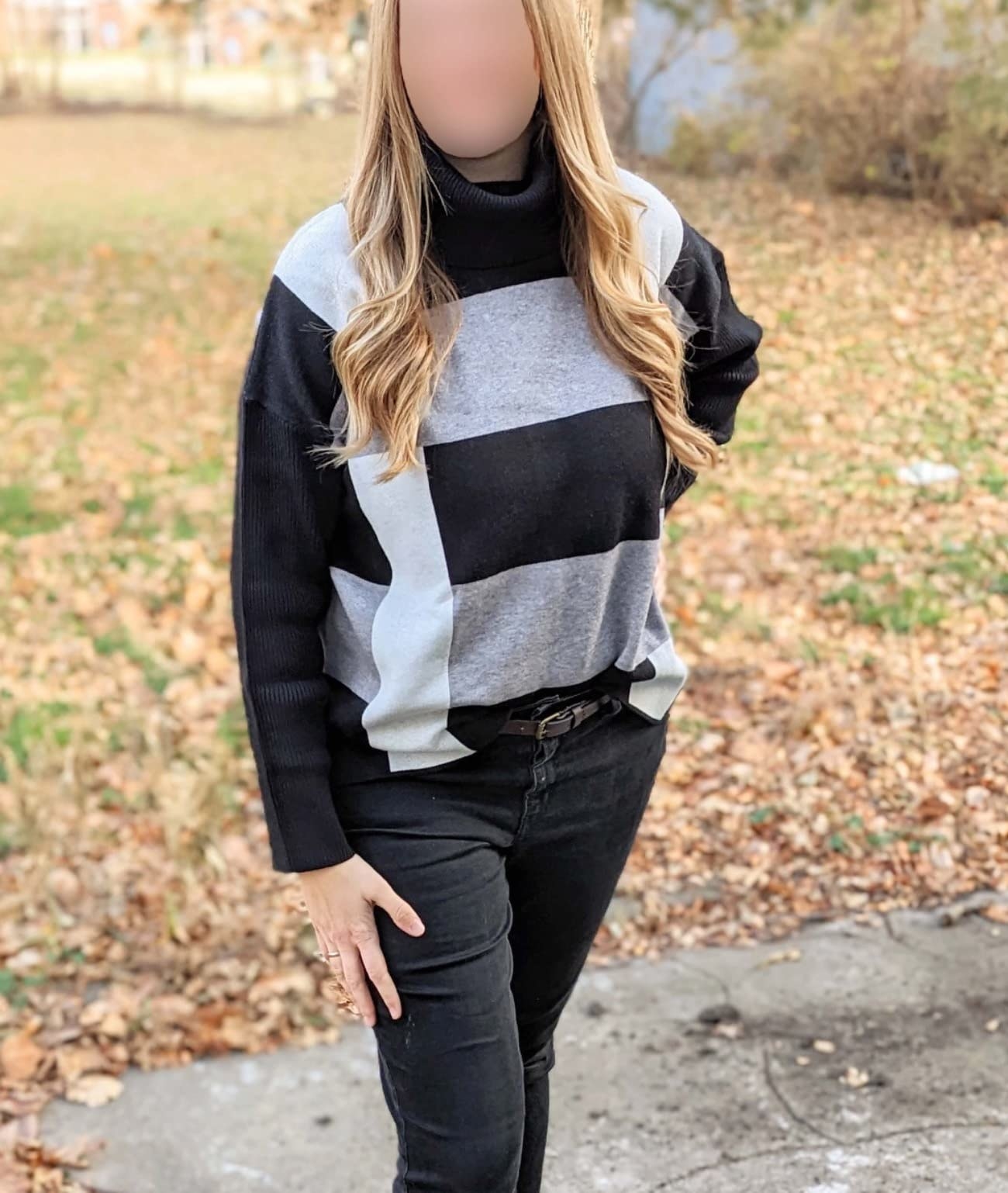 Reviewer wearing the grey, black, and white colorblock sweater tucked into black jeans