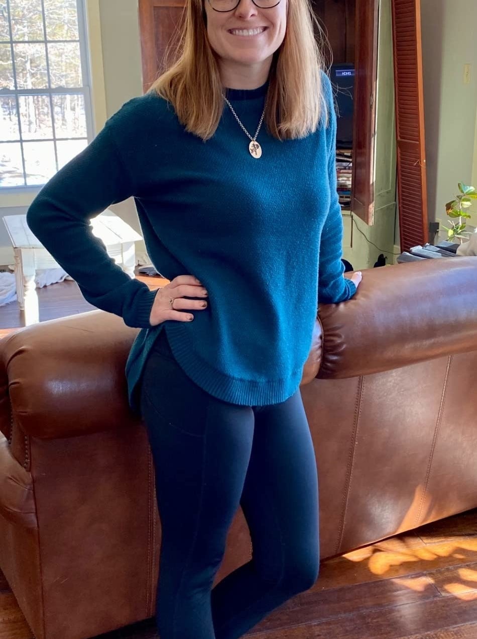 reviewer wearing the blue sweater with gold necklace and leggings