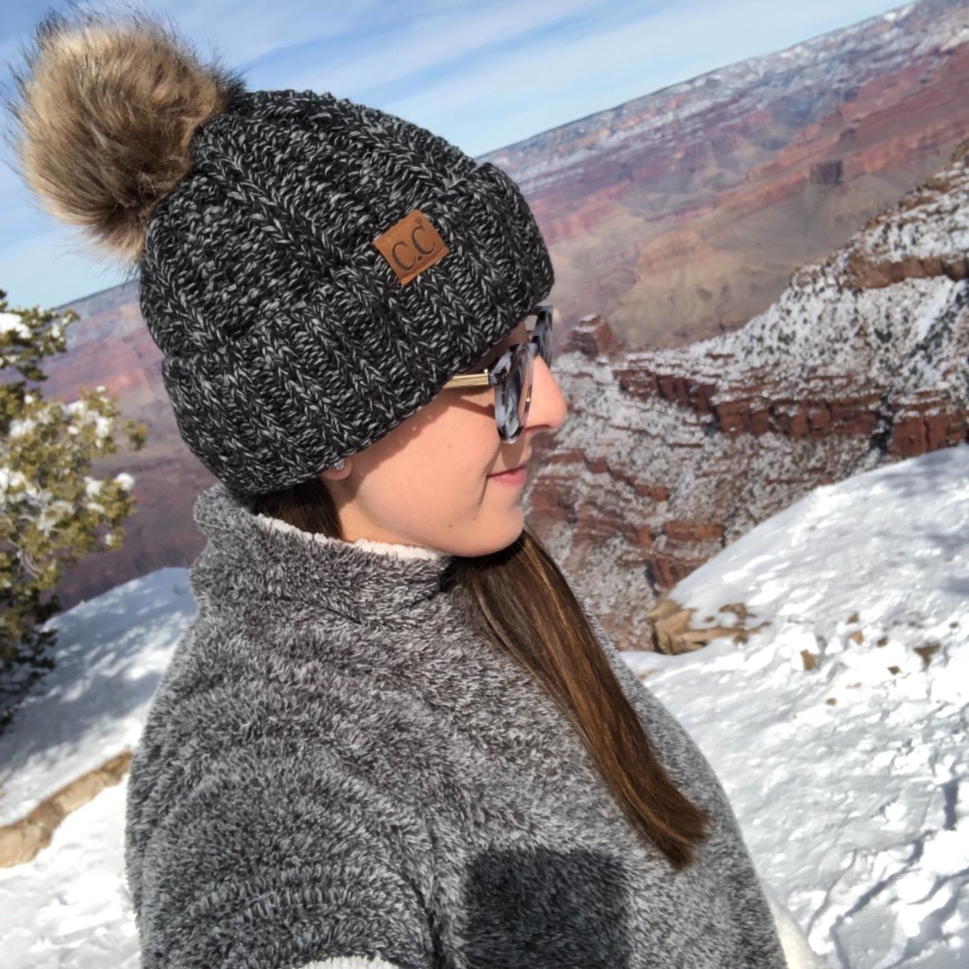 A person wearing the black beanie outside with snowy canyon landscape in the background