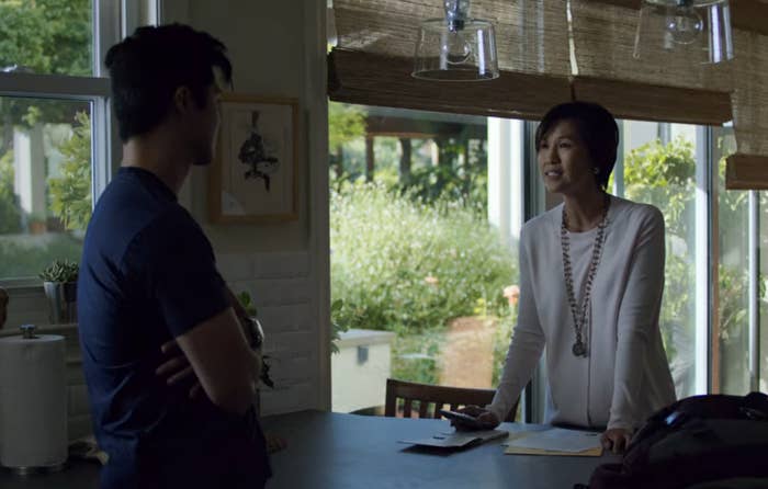 A mother and son standing across from each other at a table