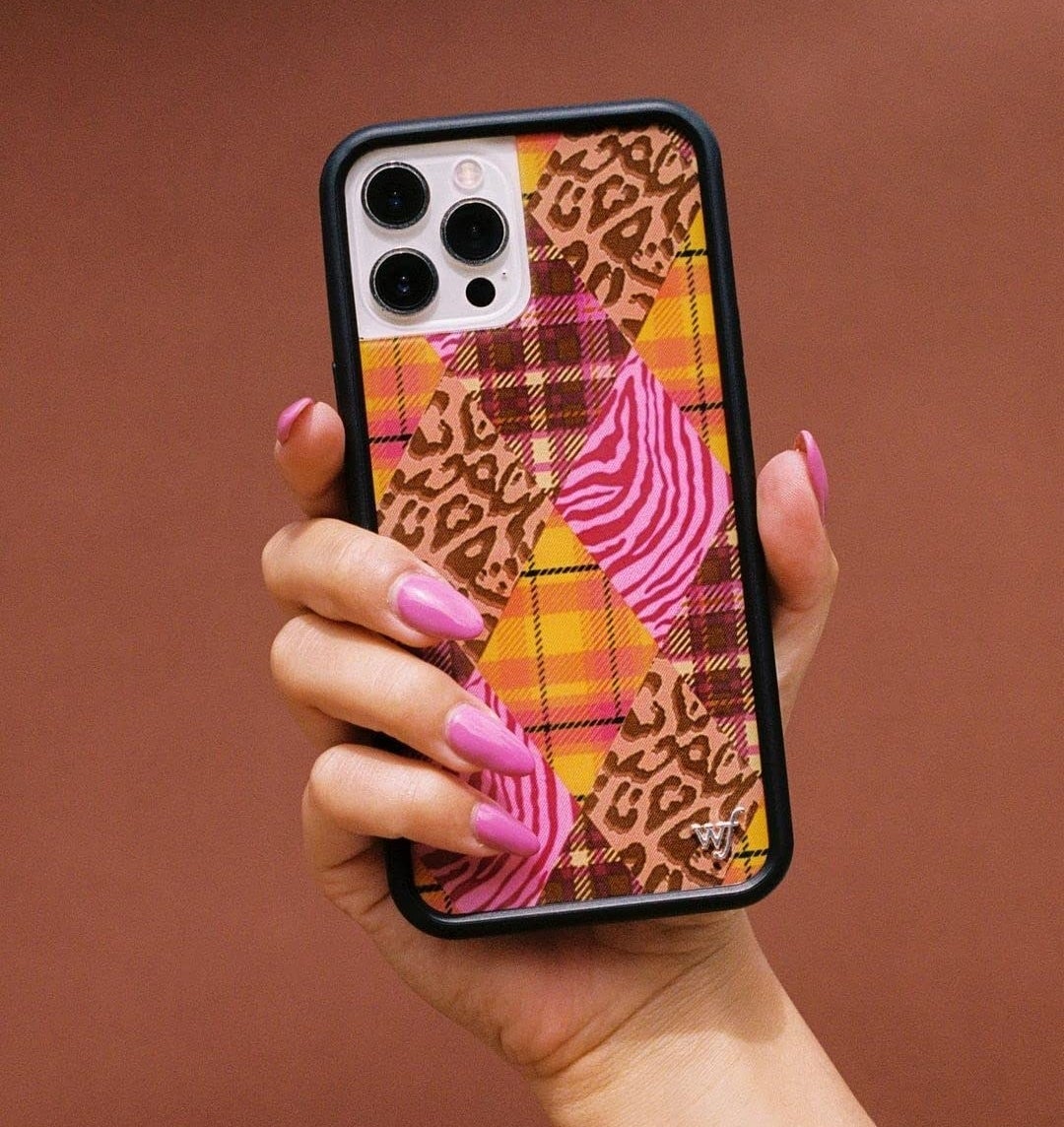 someone holding up the patterned phone case against a colourful wall