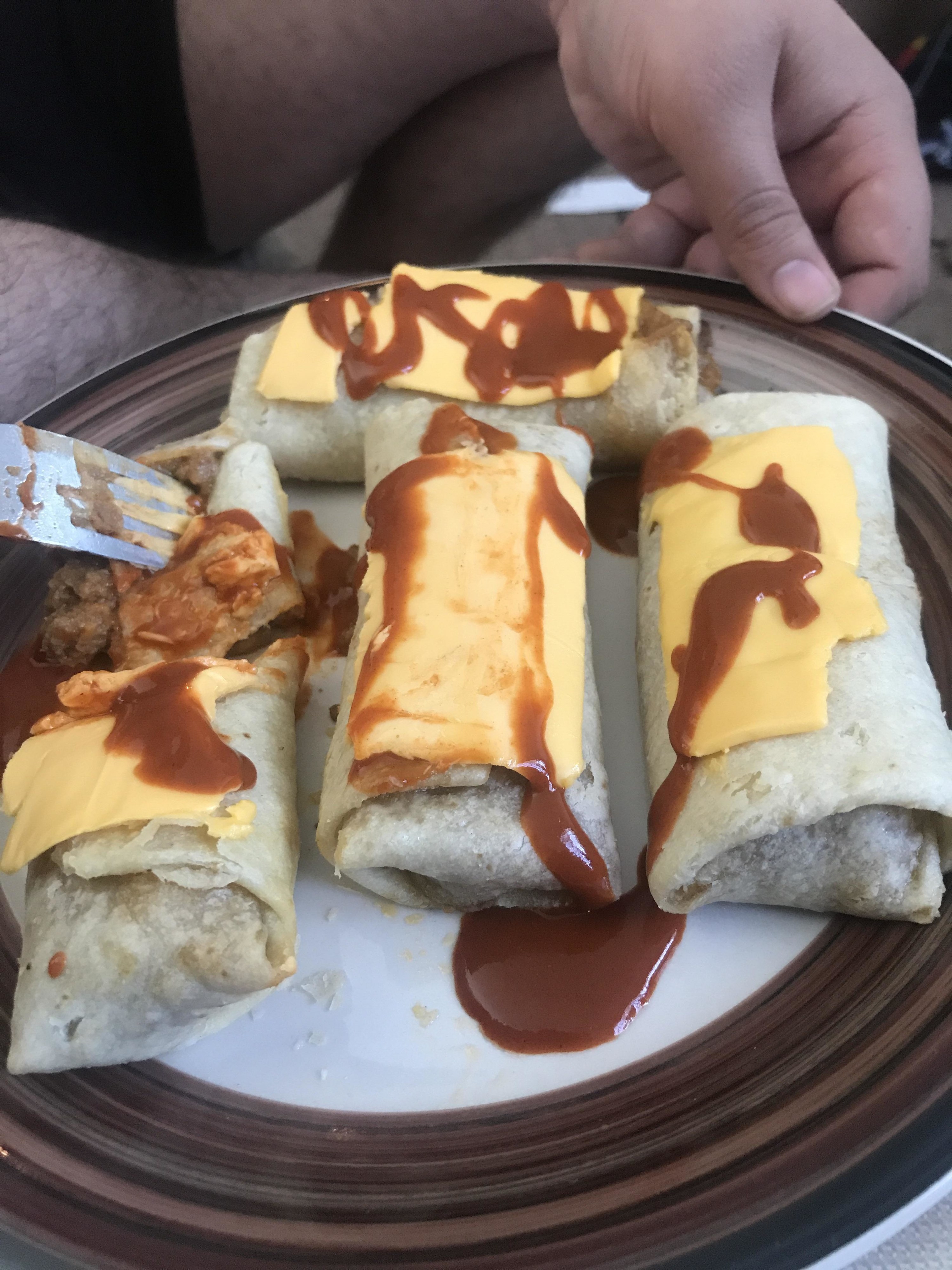 frozen burritos covered in sliced american cheese and hot sauce