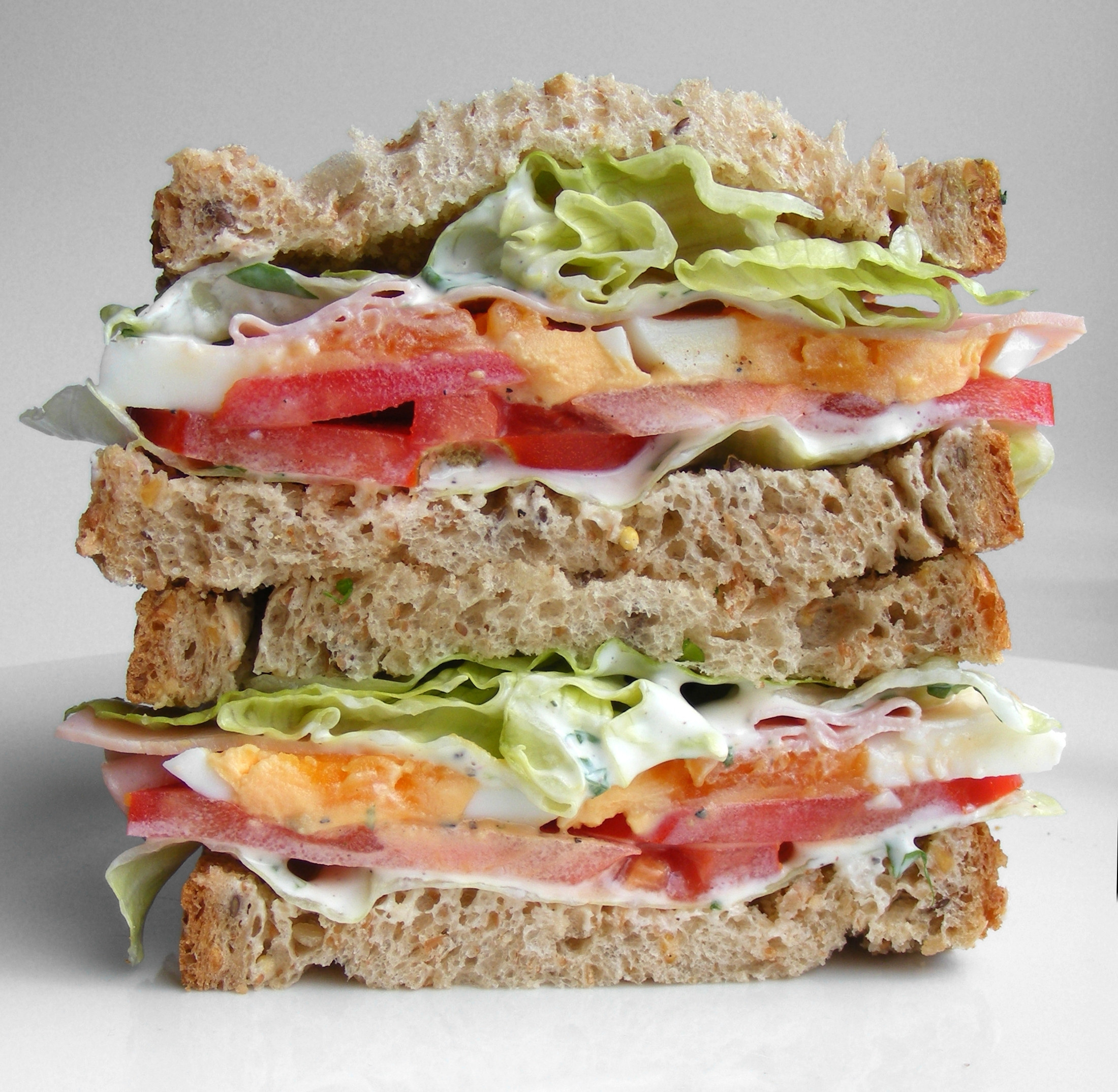 Sandwich with iceberg lettuce, tomato, egg, ham and mayo.