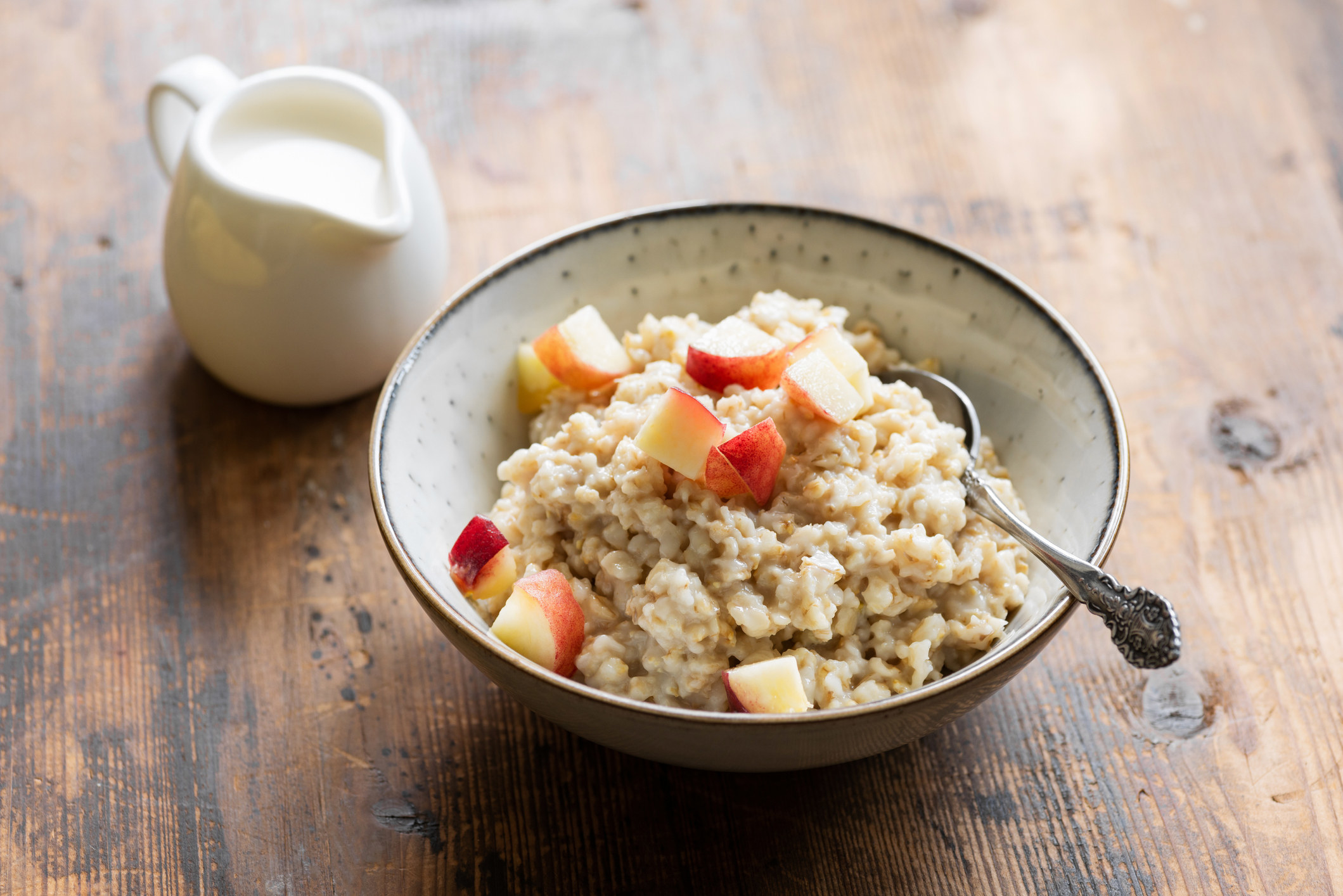 Oatmeal porridge with peach in bowl.