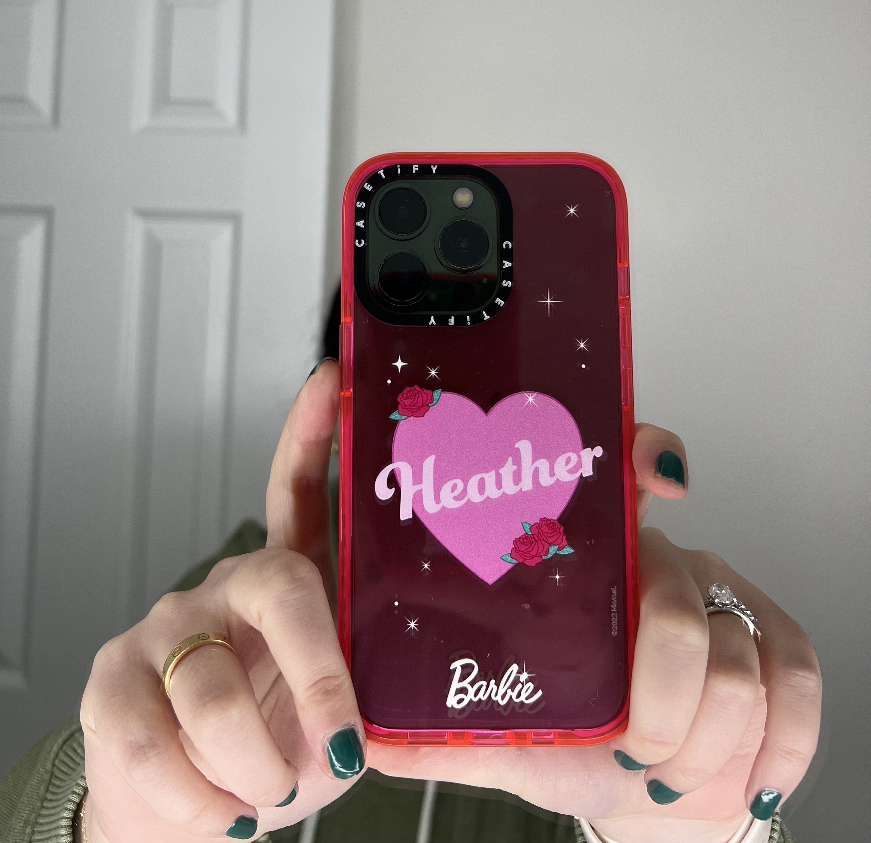 a pink phone case with a heart in the middle that says &quot;heather&quot; and the barbie logo