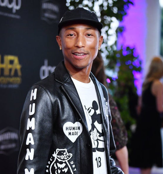 pharrell wearing a human made leather jacket and a mickey moues shirt and a baseball had