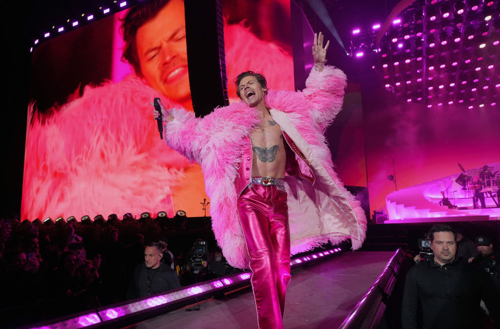 A bare-chested Harry onstage with a fur coat and shiny pink pants
