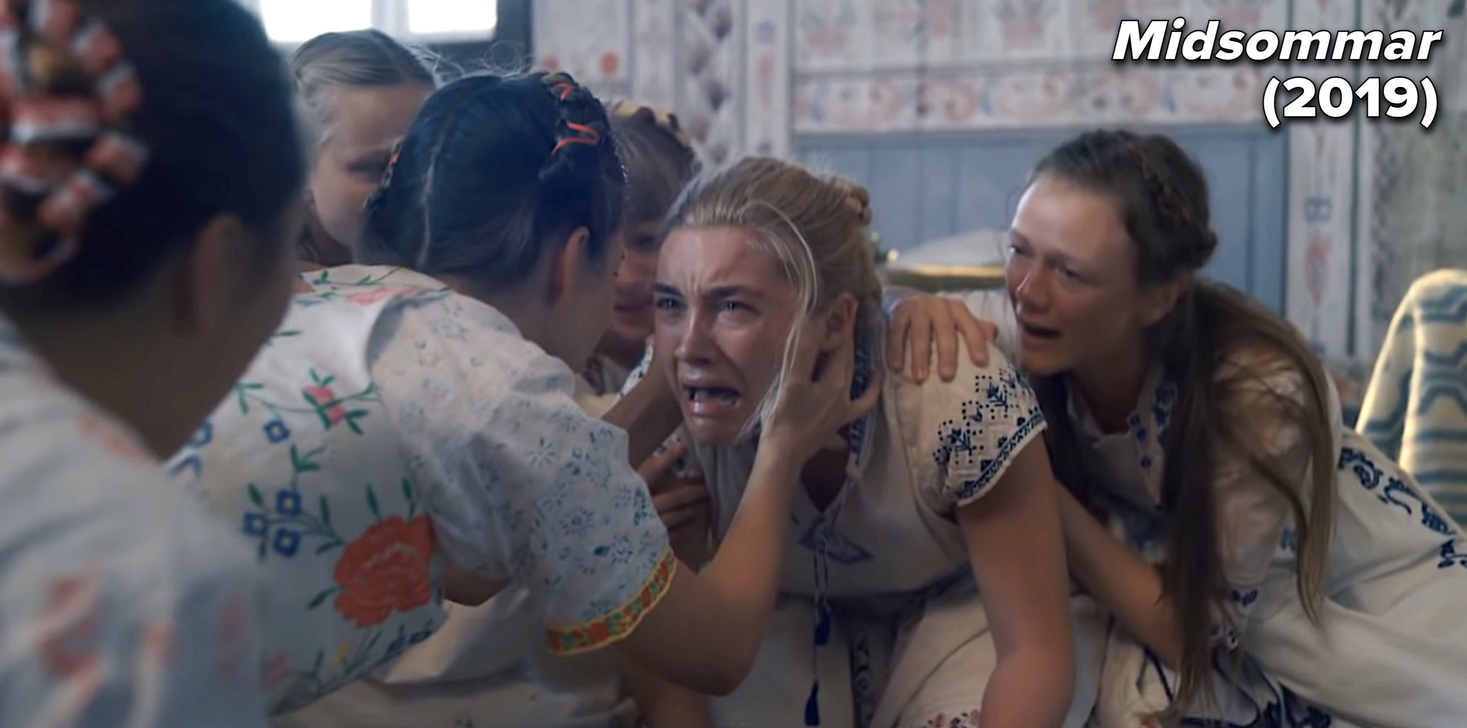 scene from midsommar of a woman crying and a group of woman surrounding her