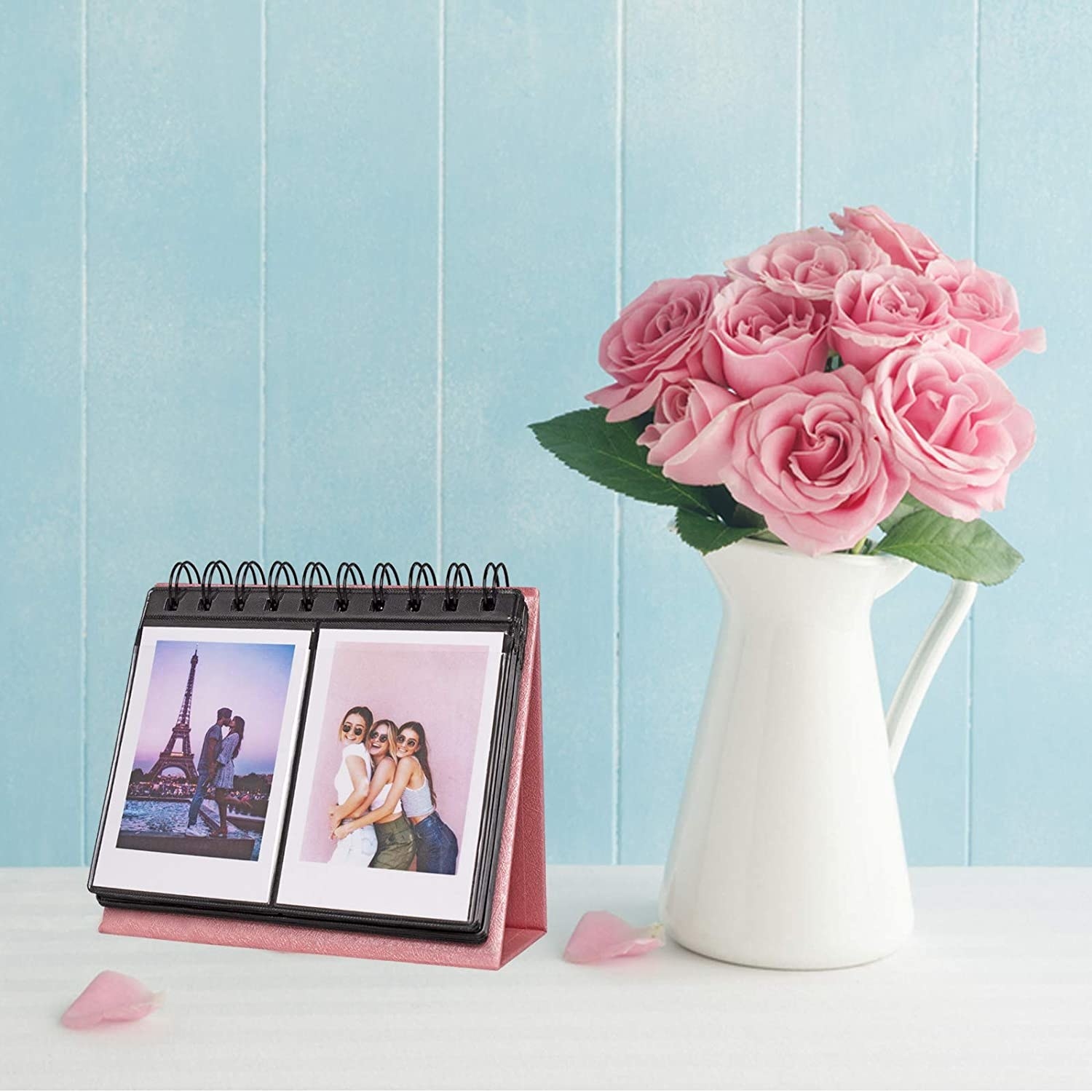 the photo album next to a vase filled with roses