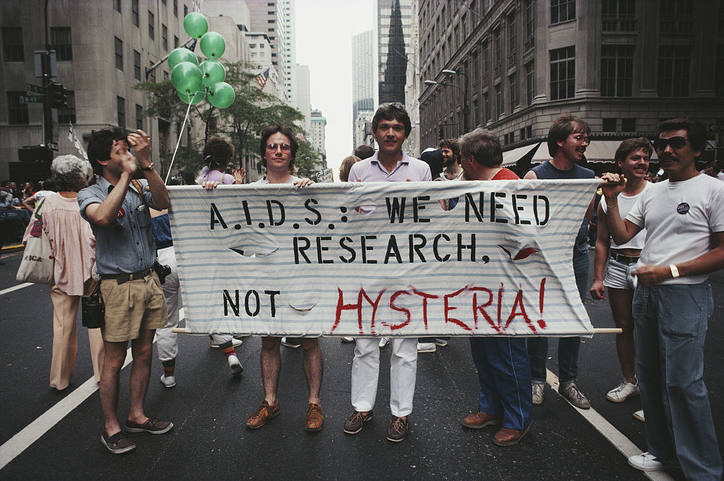 Protesters marching with a banner that says &quot;AIDS we need research not hysteria&quot;