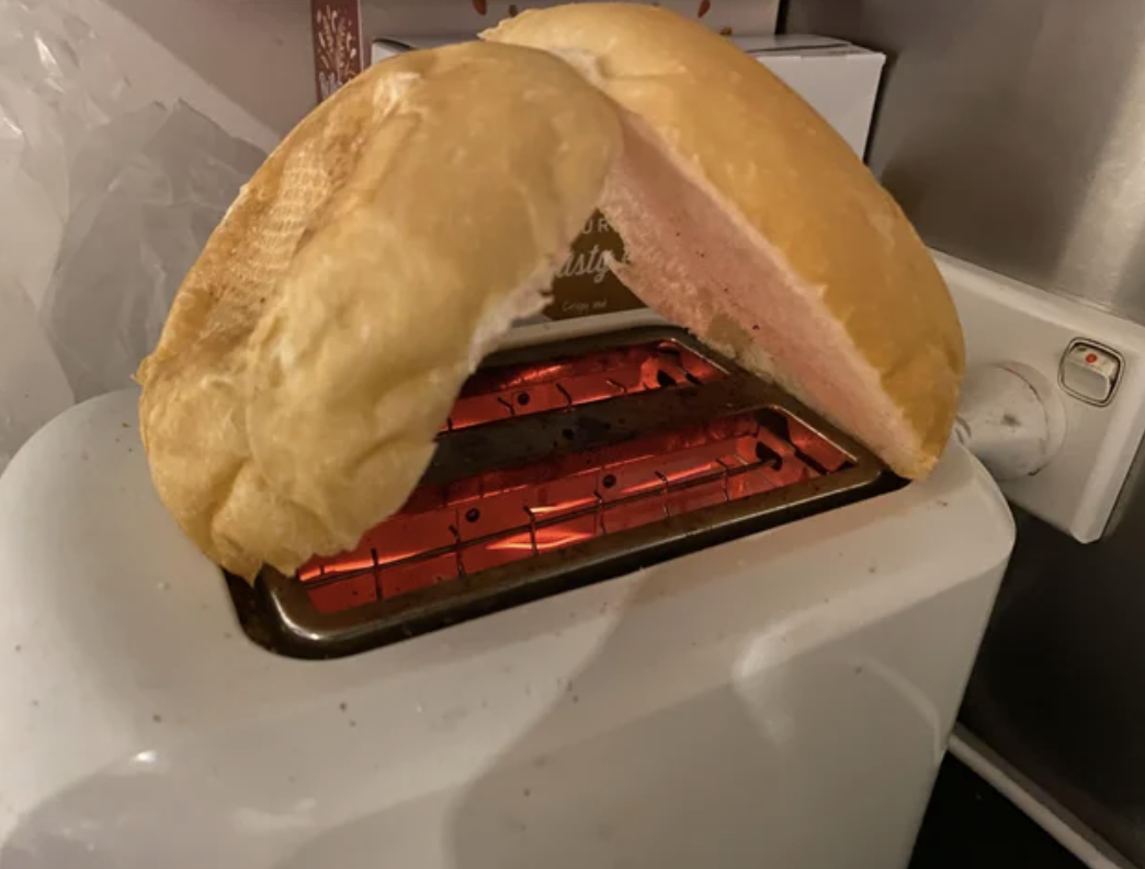 a hamburger bun toasting on top of a toaster by having each side lean on the other