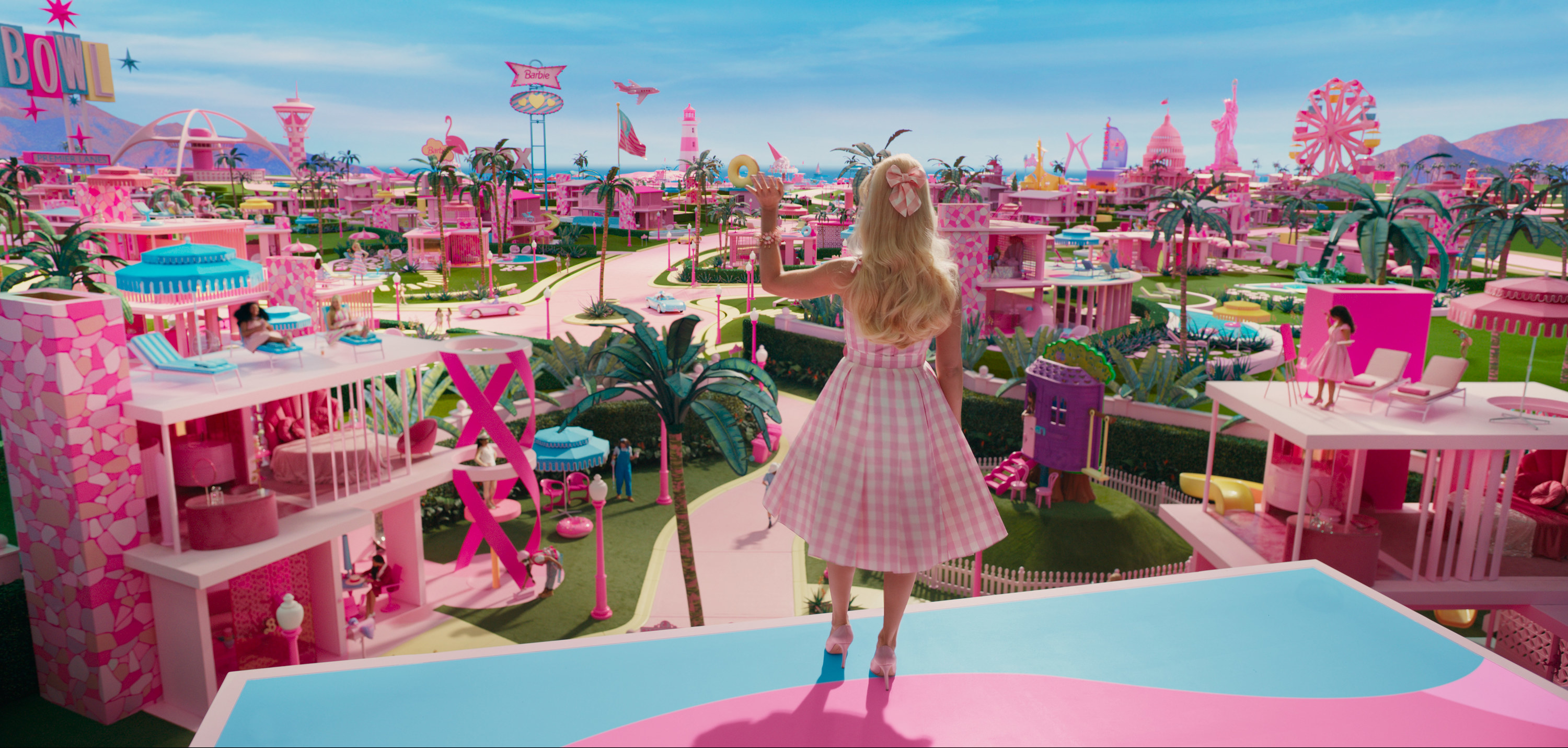 Barbie looking at her very pink dream world with many Barbie houses on the grass