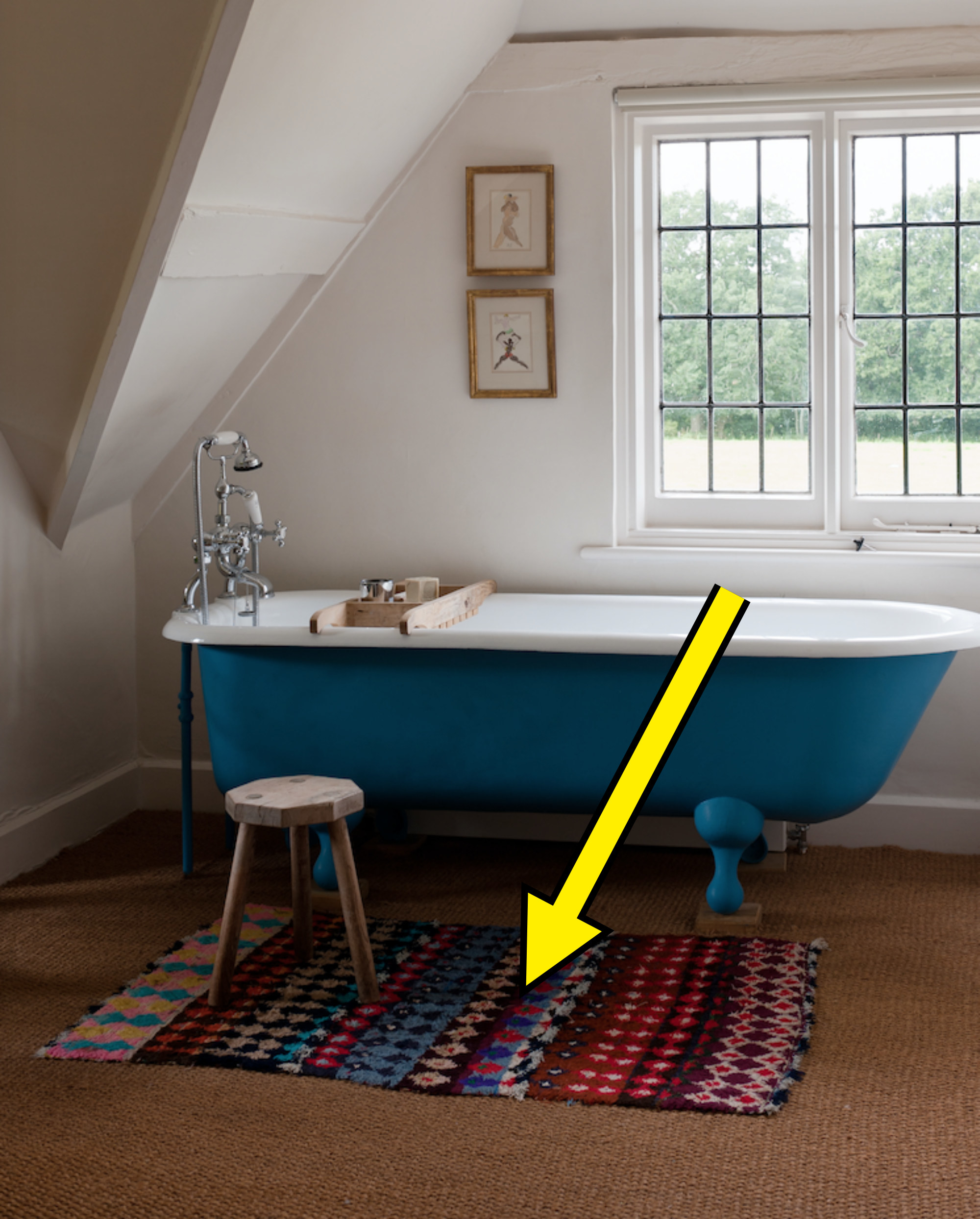 blue clawfoot tub with bold patterned rug next to it
