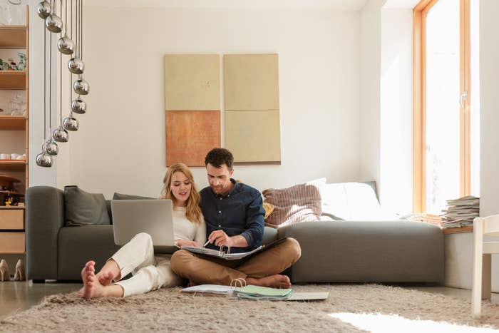 Man and woman looking at papers and laptop in living room