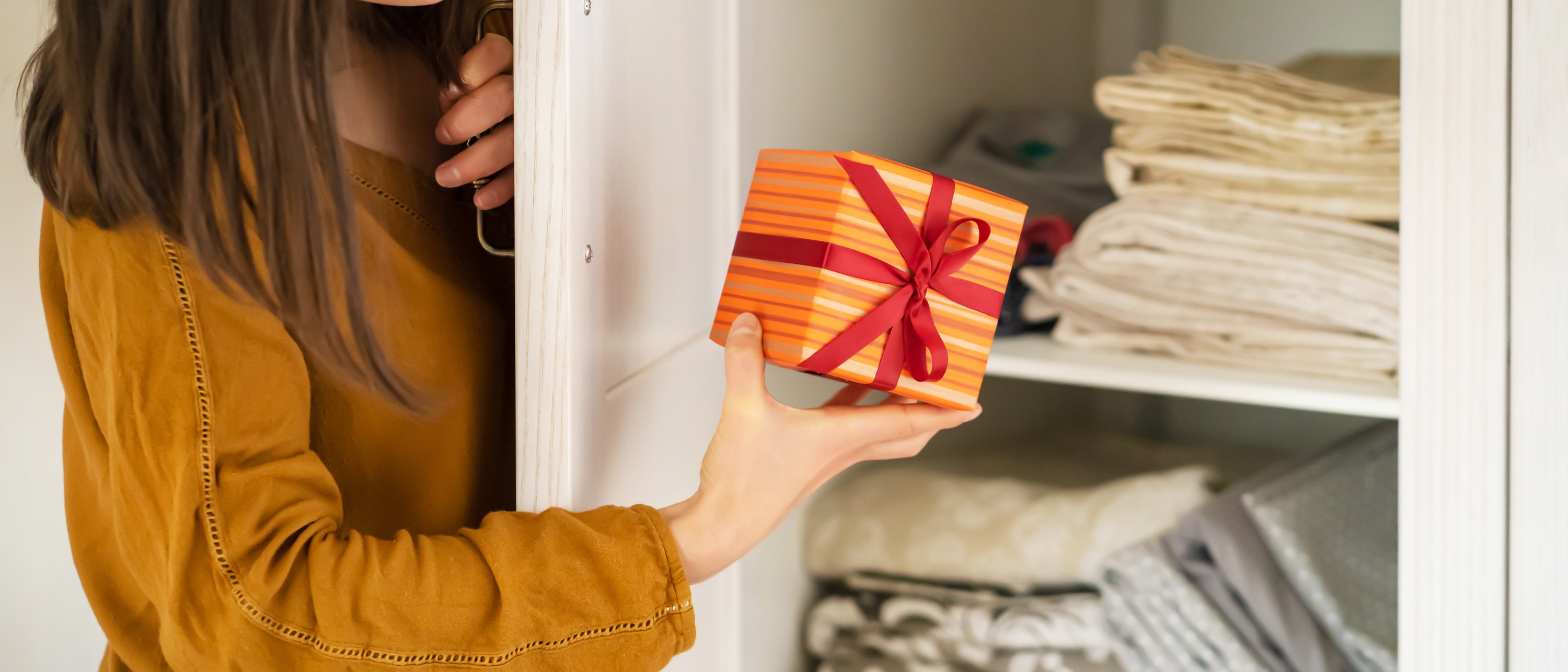 A funny young girl is in a hurry to hide a gift for a loved one, husband, children, friends and parents, a woman wants to make a surprise and hides the gift in the closet during holidays