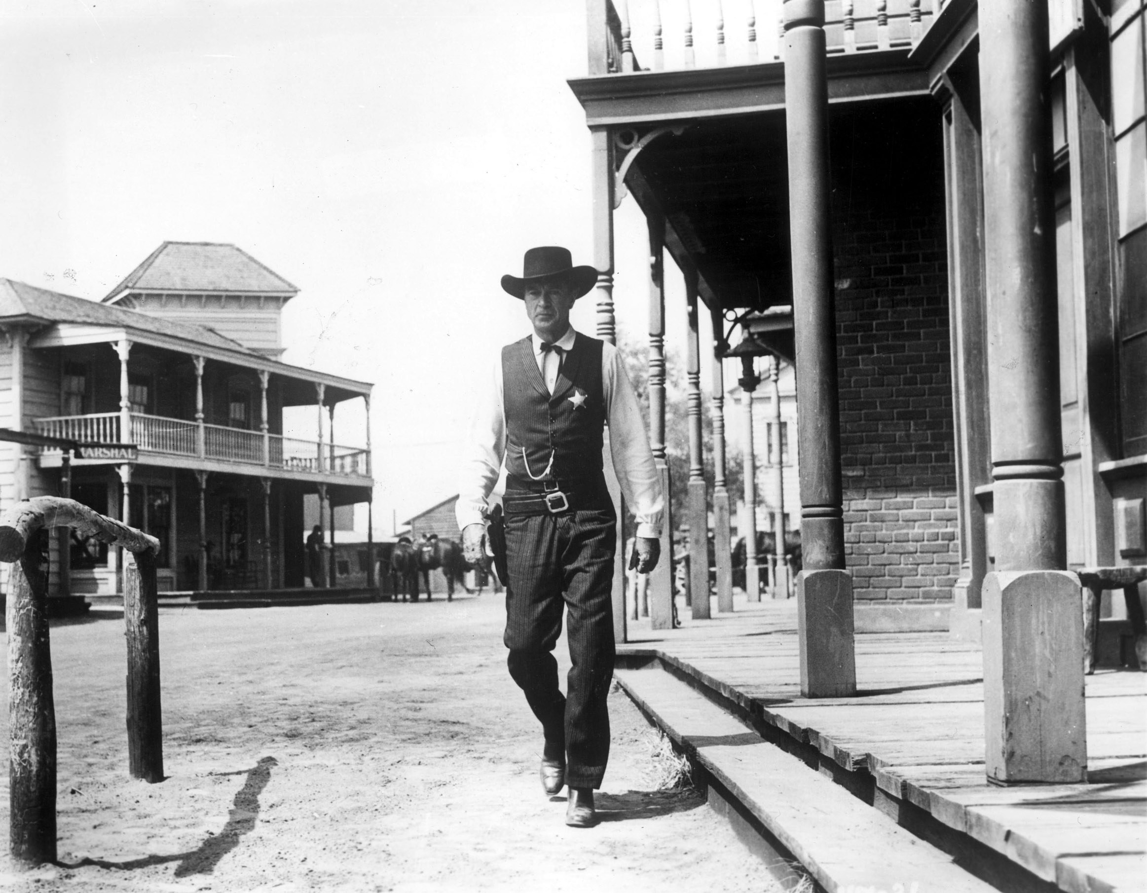 Gary Cooper walking through an Old West town.