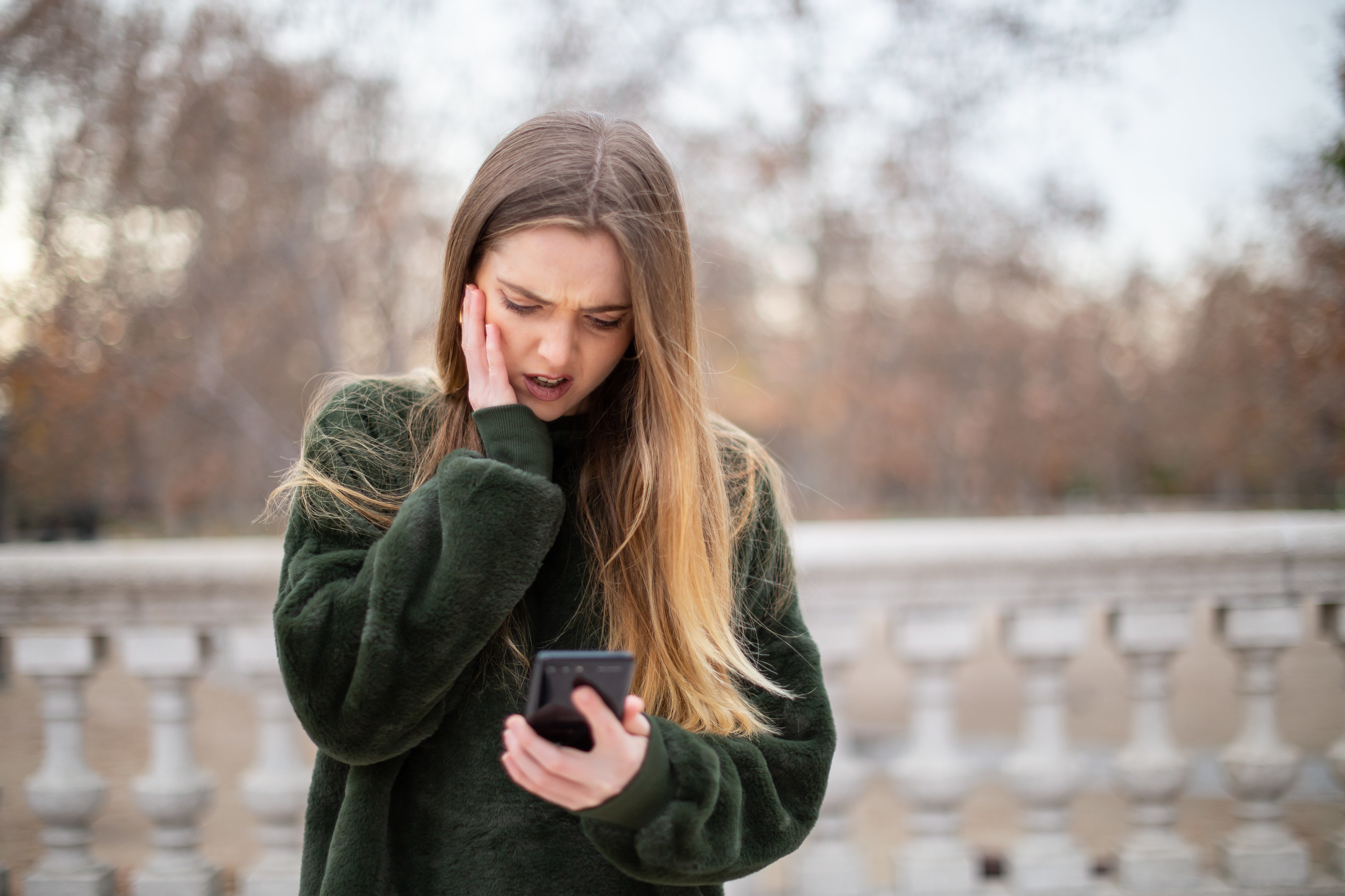 A girl looking at her phone with her hand on her cheek