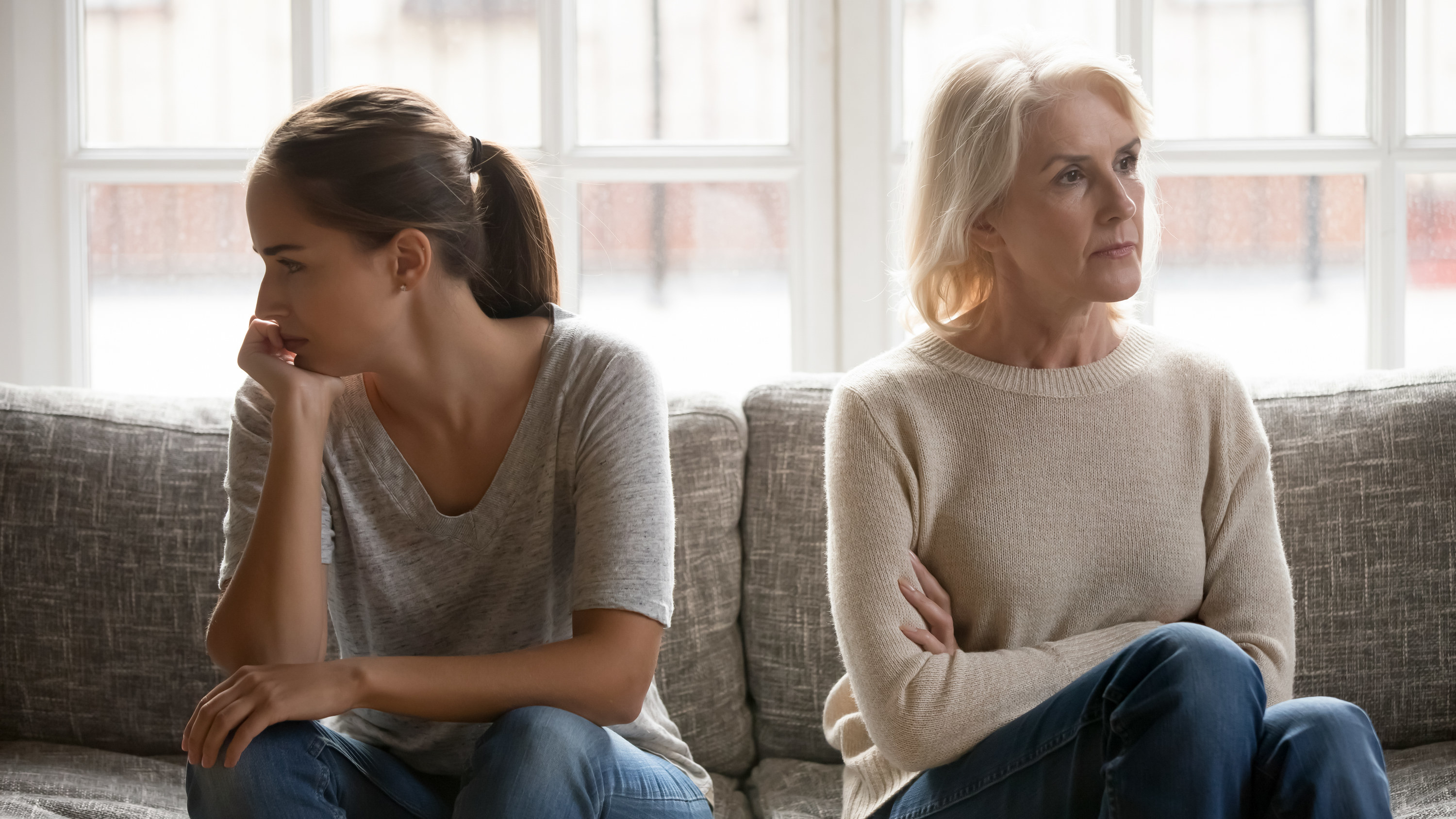 A mother and daughter sitting on the couch and not looking at them