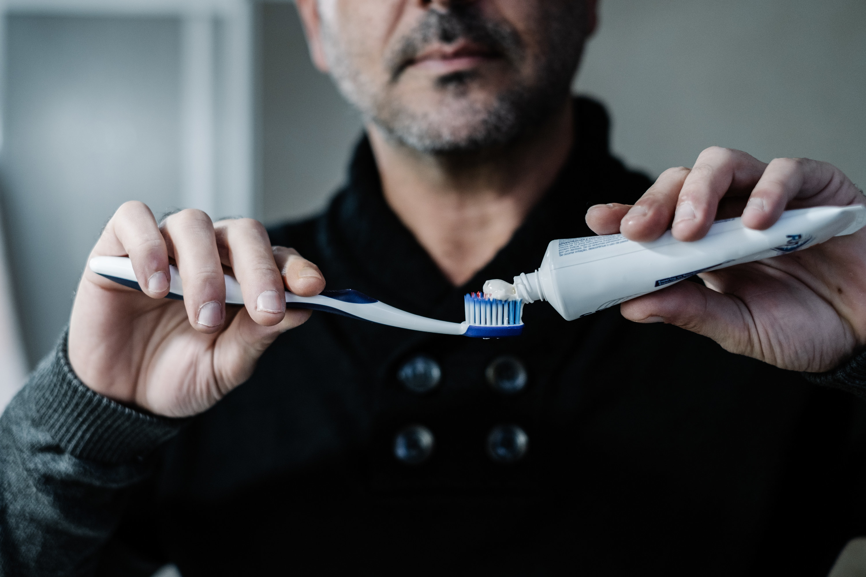 A man putting toothpaste onto a toothbrush