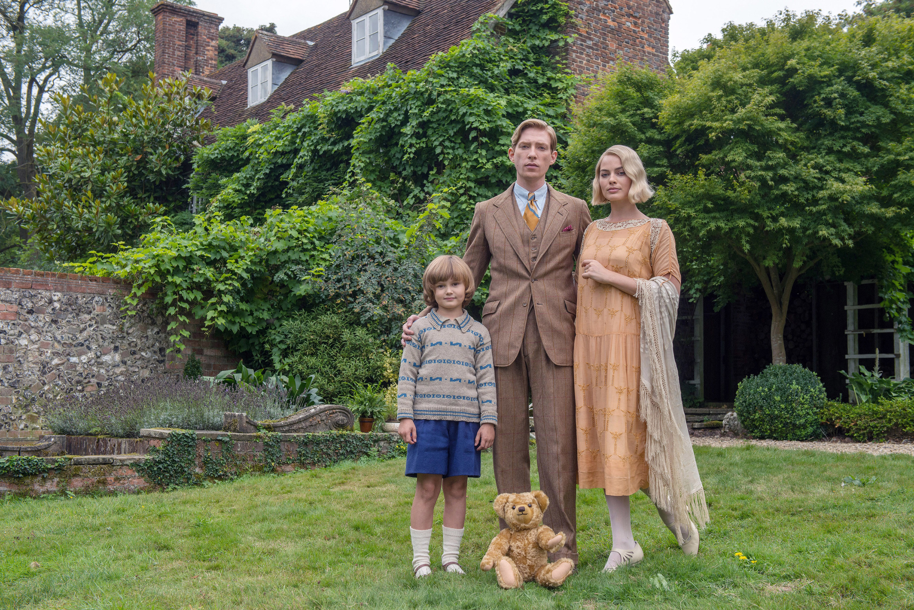 Will Tilston, Domnhall Gleeson, and Margot Robbie stand in front of a house