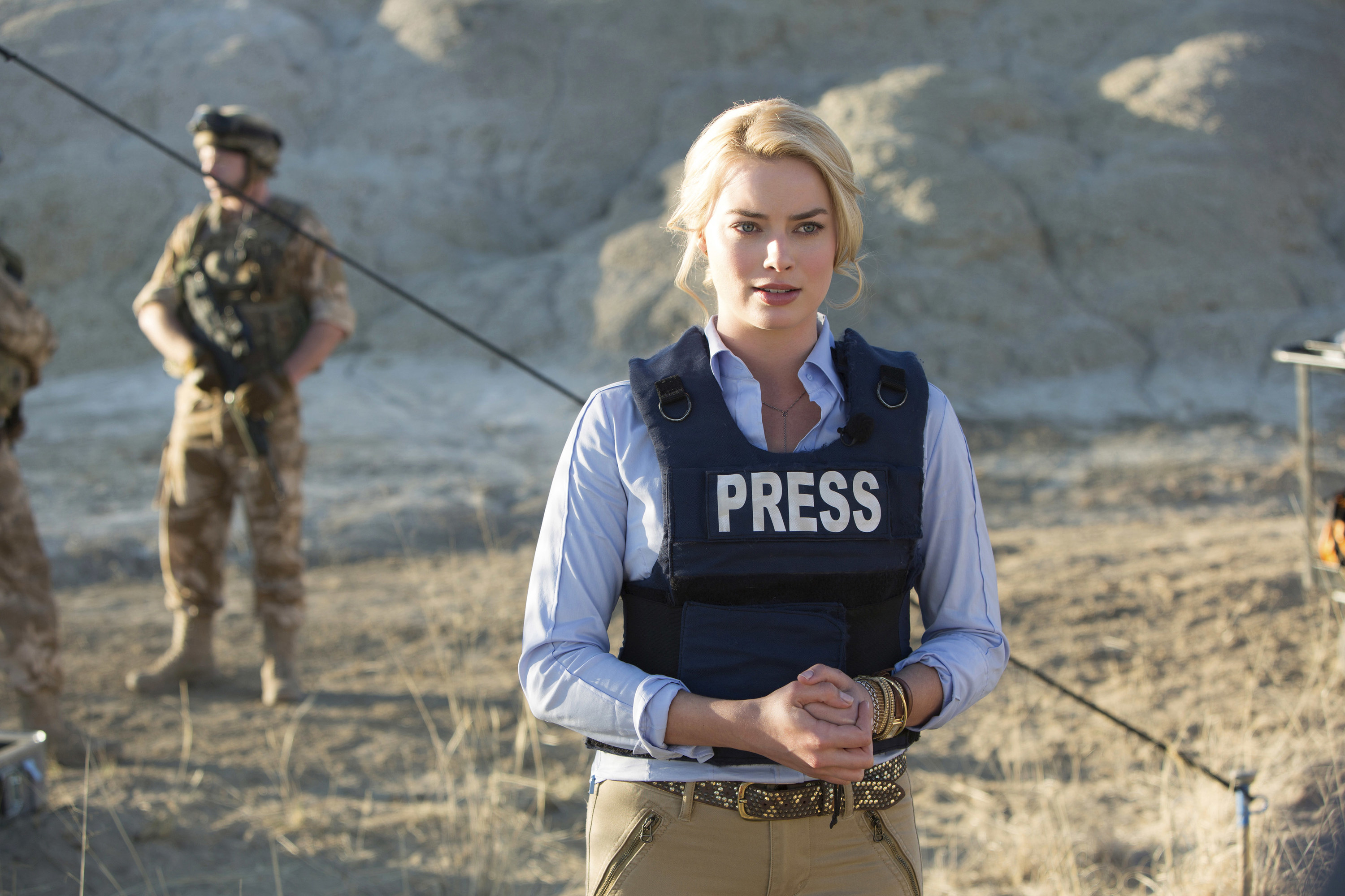 Margot Robbie stands with a press vest on