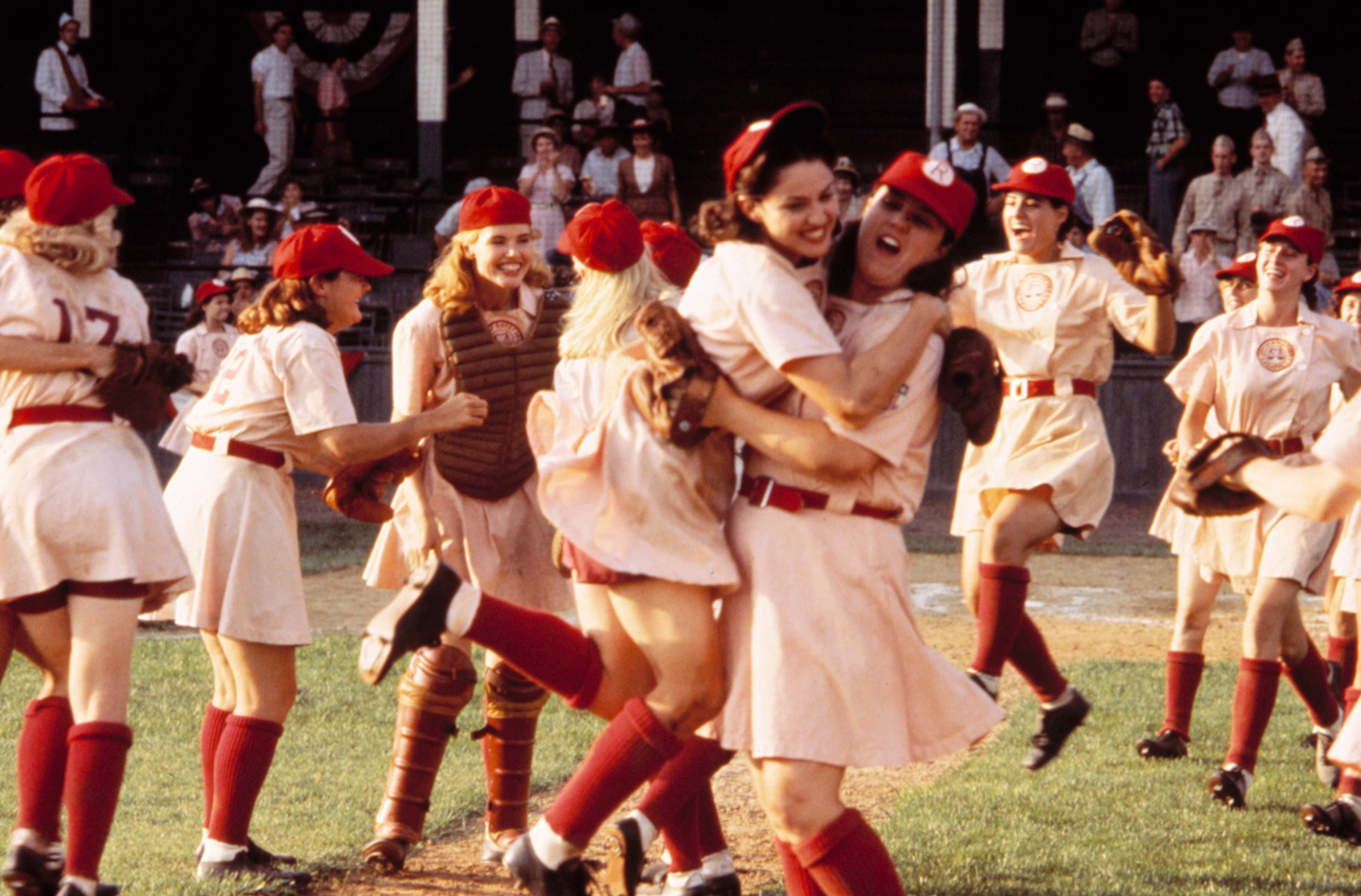 Women baseball players celebrating on the field, with Madonna and Rosie O&#x27;Donnell hugging