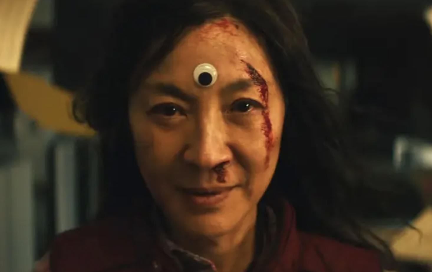 michelle yeoh in everything everywhere all at once, with blood on her brow and a googly eye sticker on her forehead