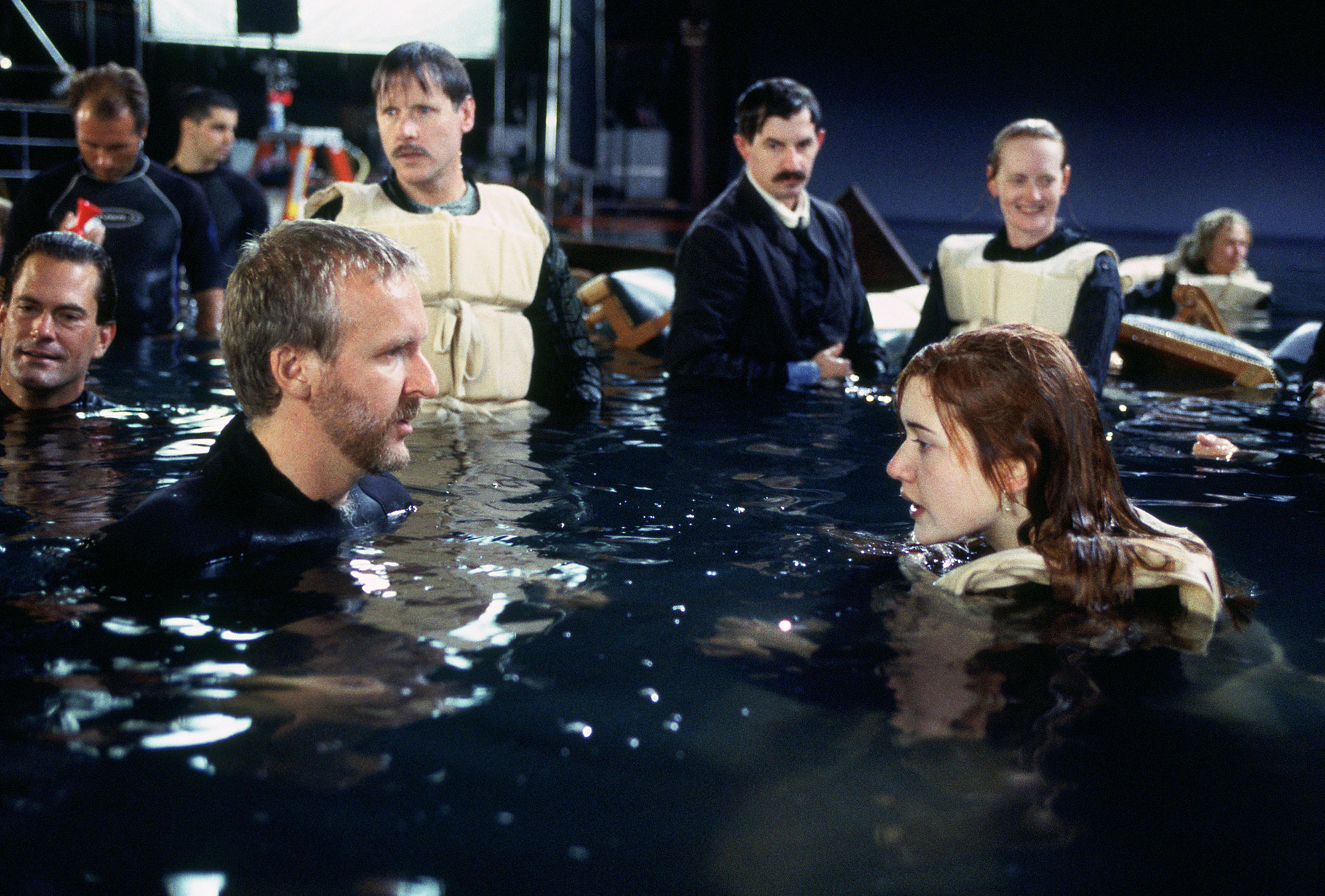 Cameron and Winslet are talking in the water, surrounded by crew