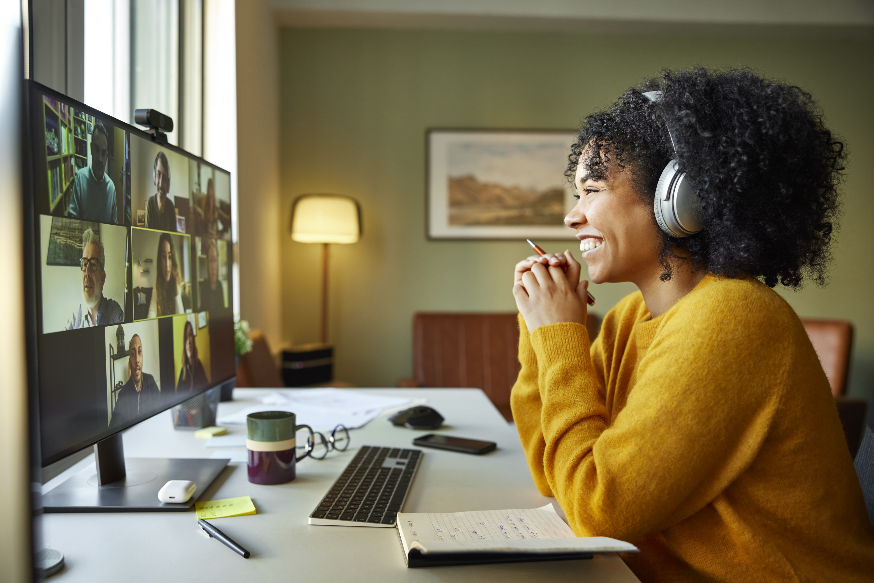 Businesswoman with headphones smiling during video conference. Multiracial male and female professionals are attending online meeting. They are discussing business strategy
