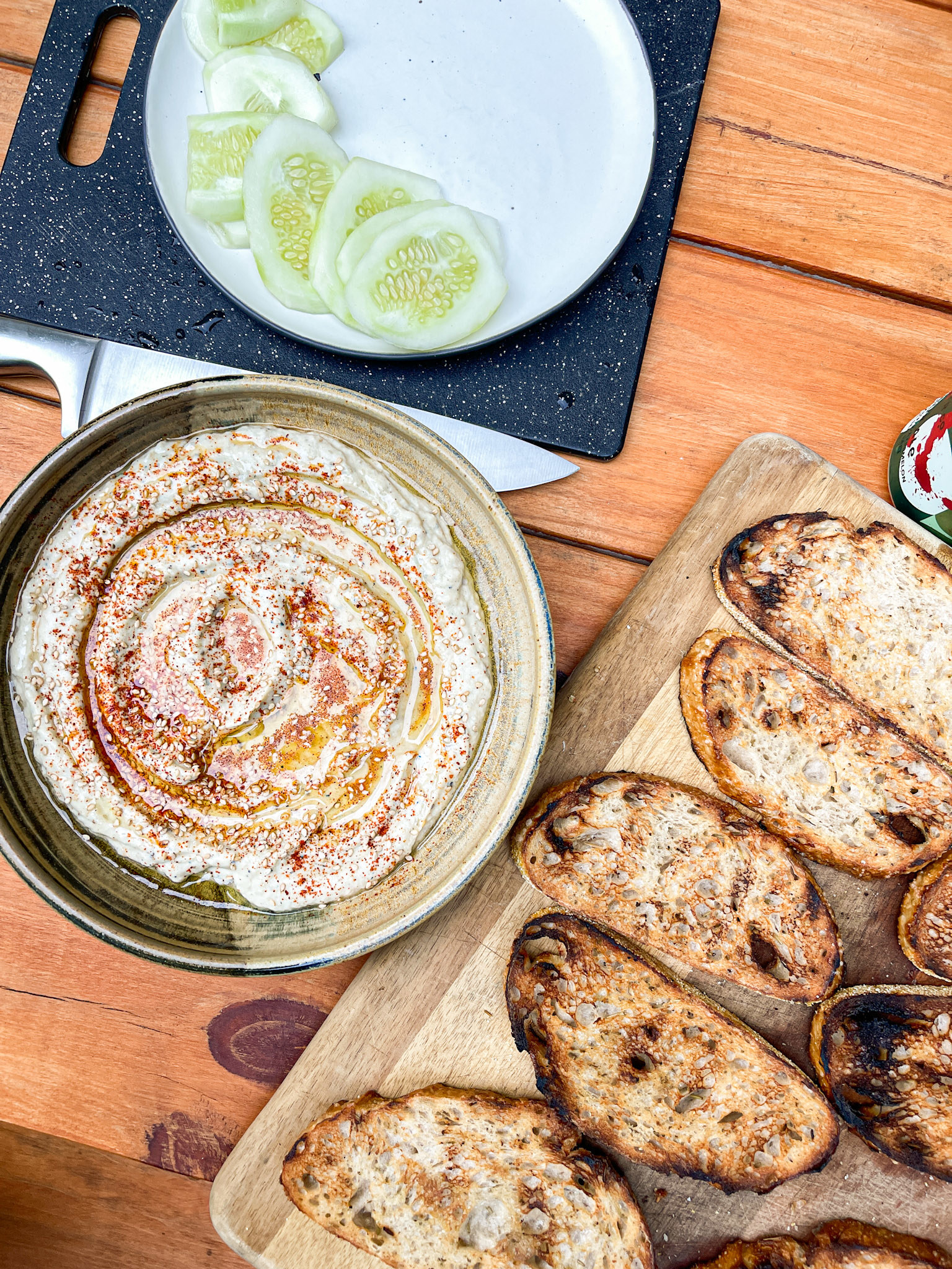 baba ganoush in a bowl next to grilled bread and cucumbers