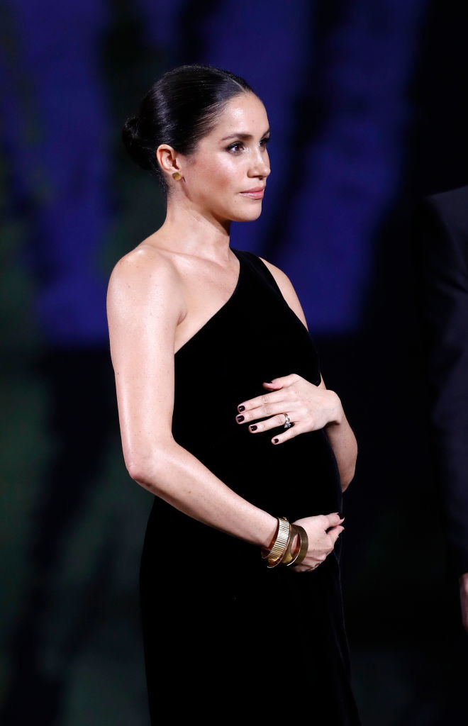 Meghan in an off-the-shoulder dress and holding her baby bump