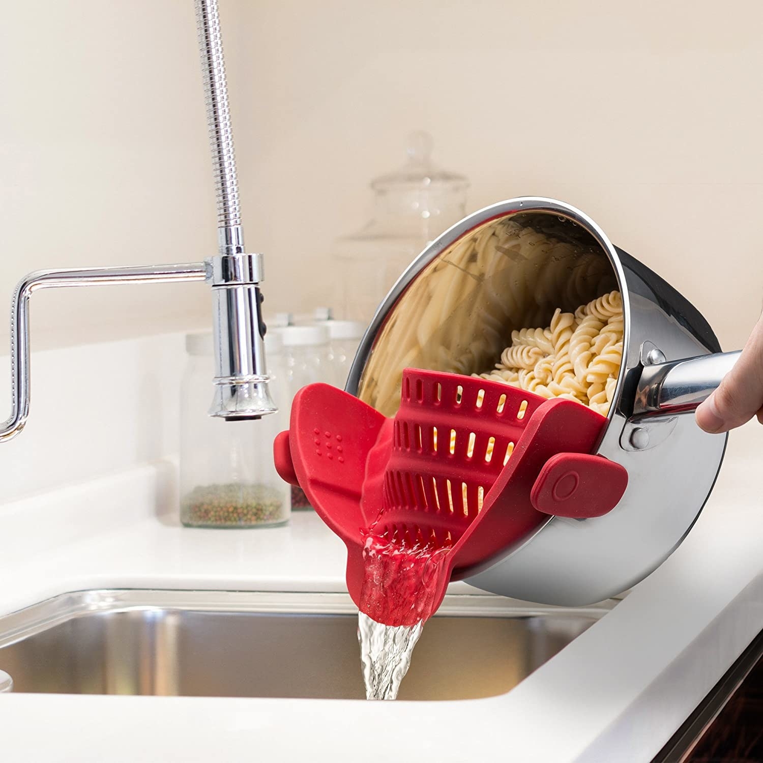 The strainer on a pot, straining pasta over a sink