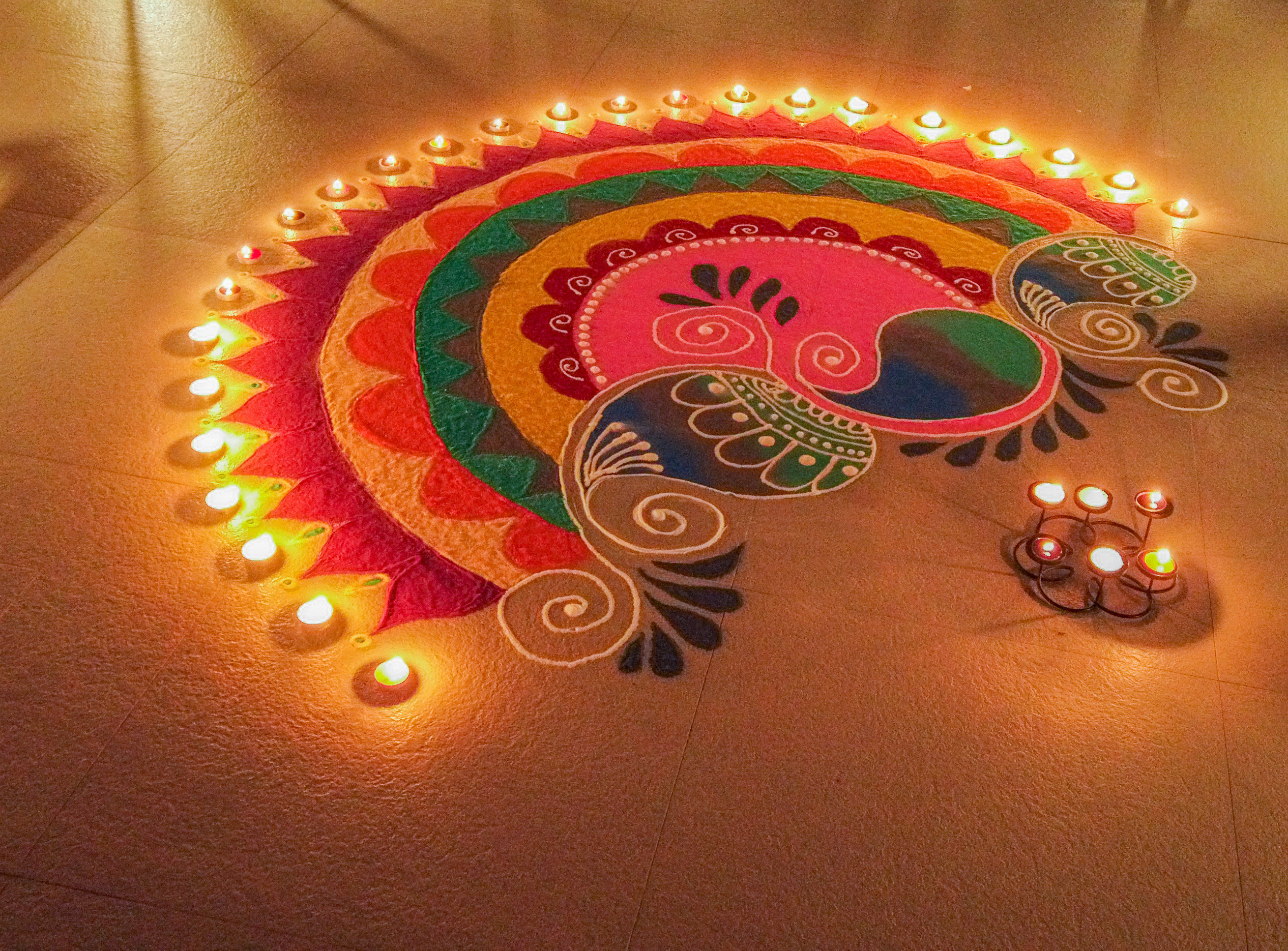 Traditional rangoli made using sand colours during Diwali days. Rangoli decorated with lamps