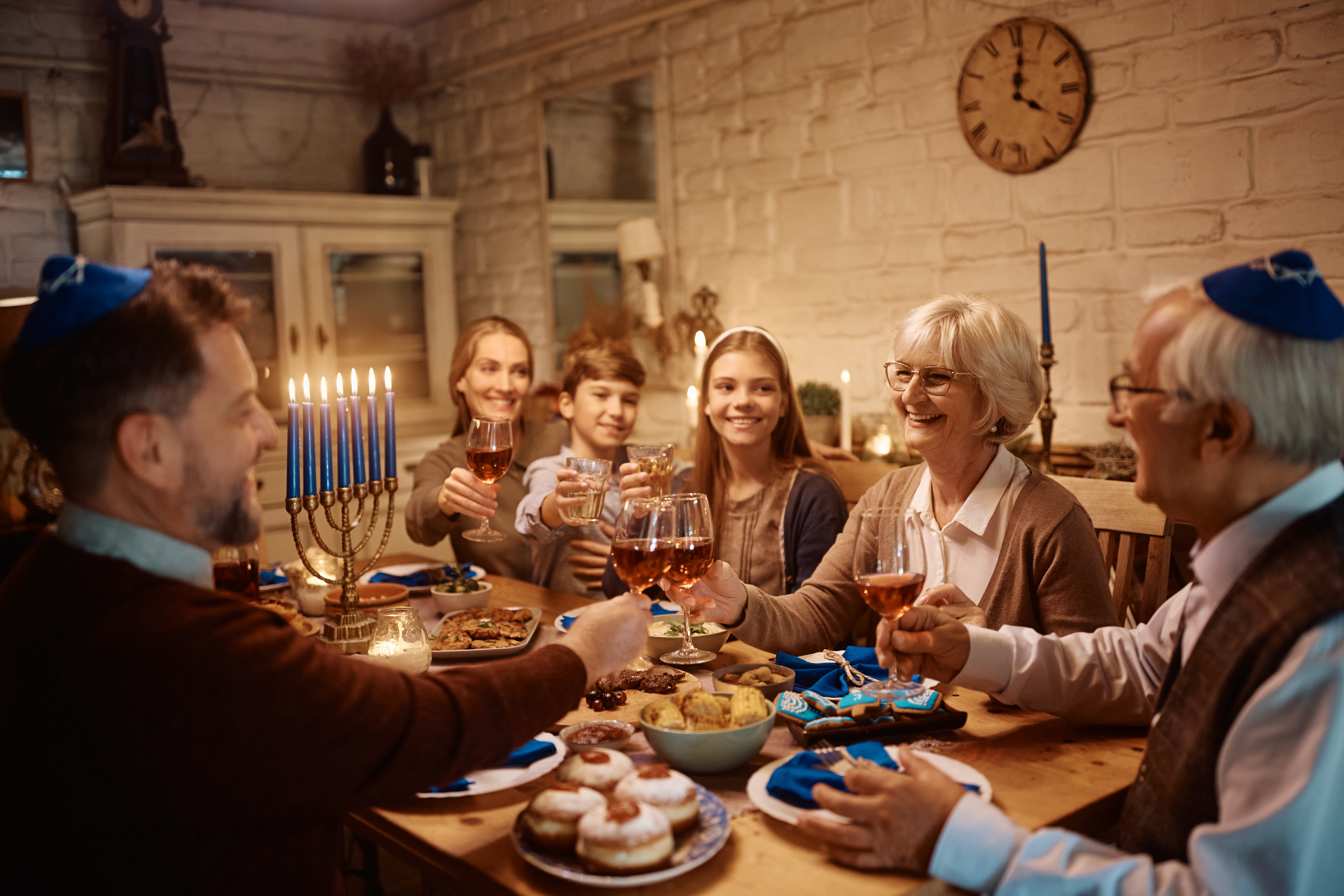 Happy senior Jewish woman toasting with her extended family during lunch at dining table