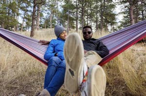 Two people relaxing in the red and purple hammock