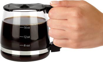 hand holding coffee mug made to look like a drip coffee glass container