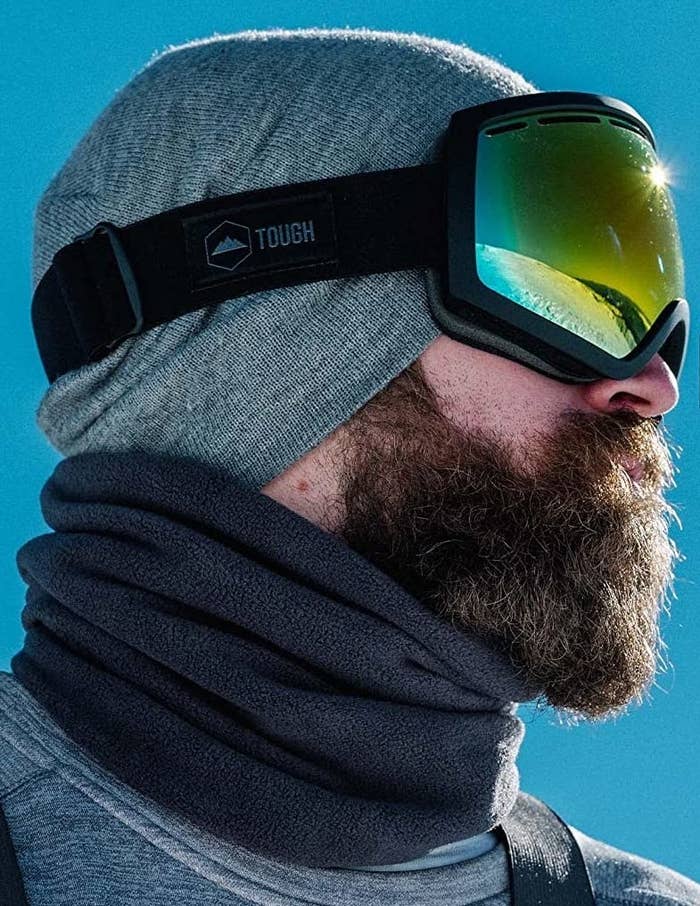 A person wearing the neck warmer, a beanie, and ski goggles